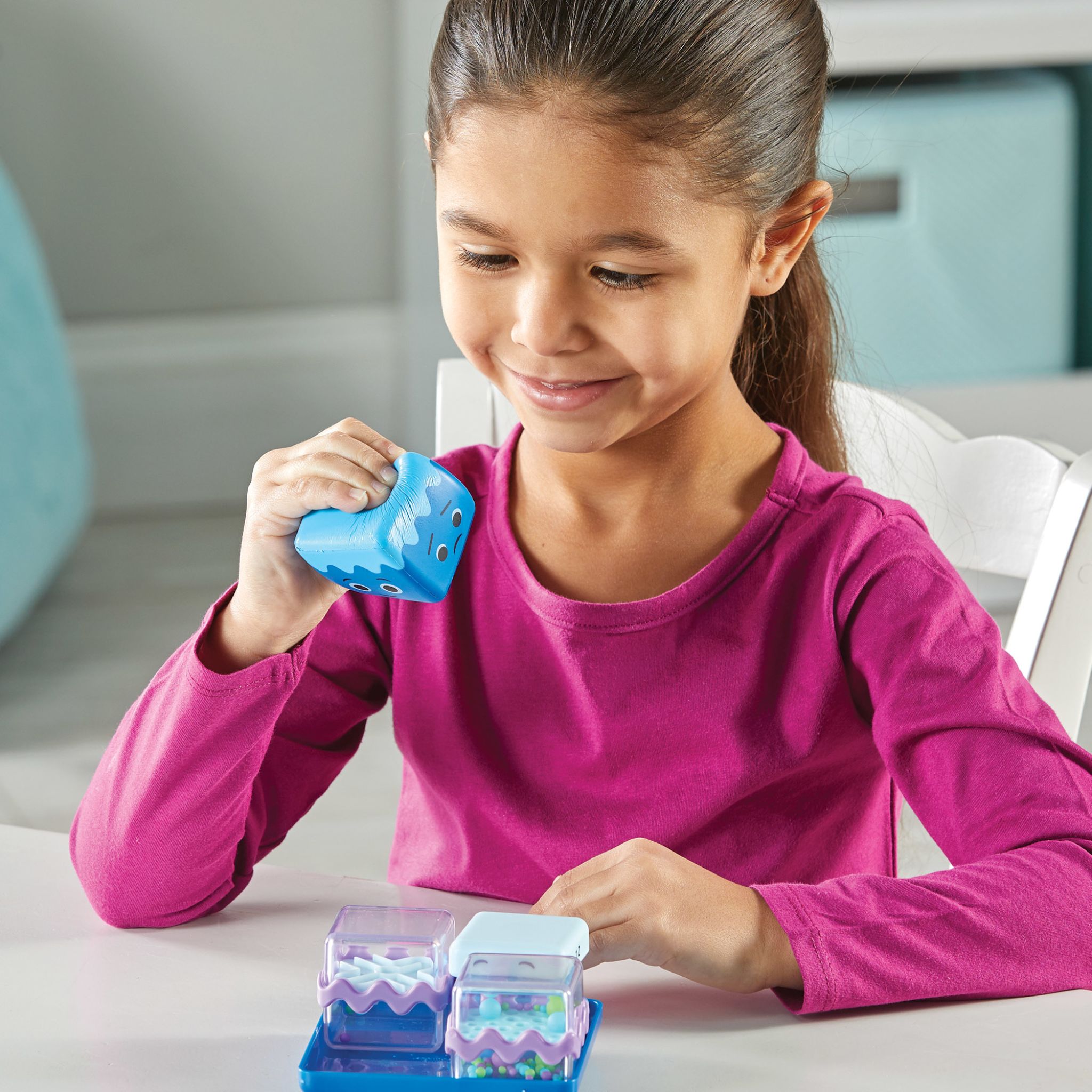 Mädchen drückt lächelnd den weichen Schaumstoffwürfel des Cool Down Cubes Sets