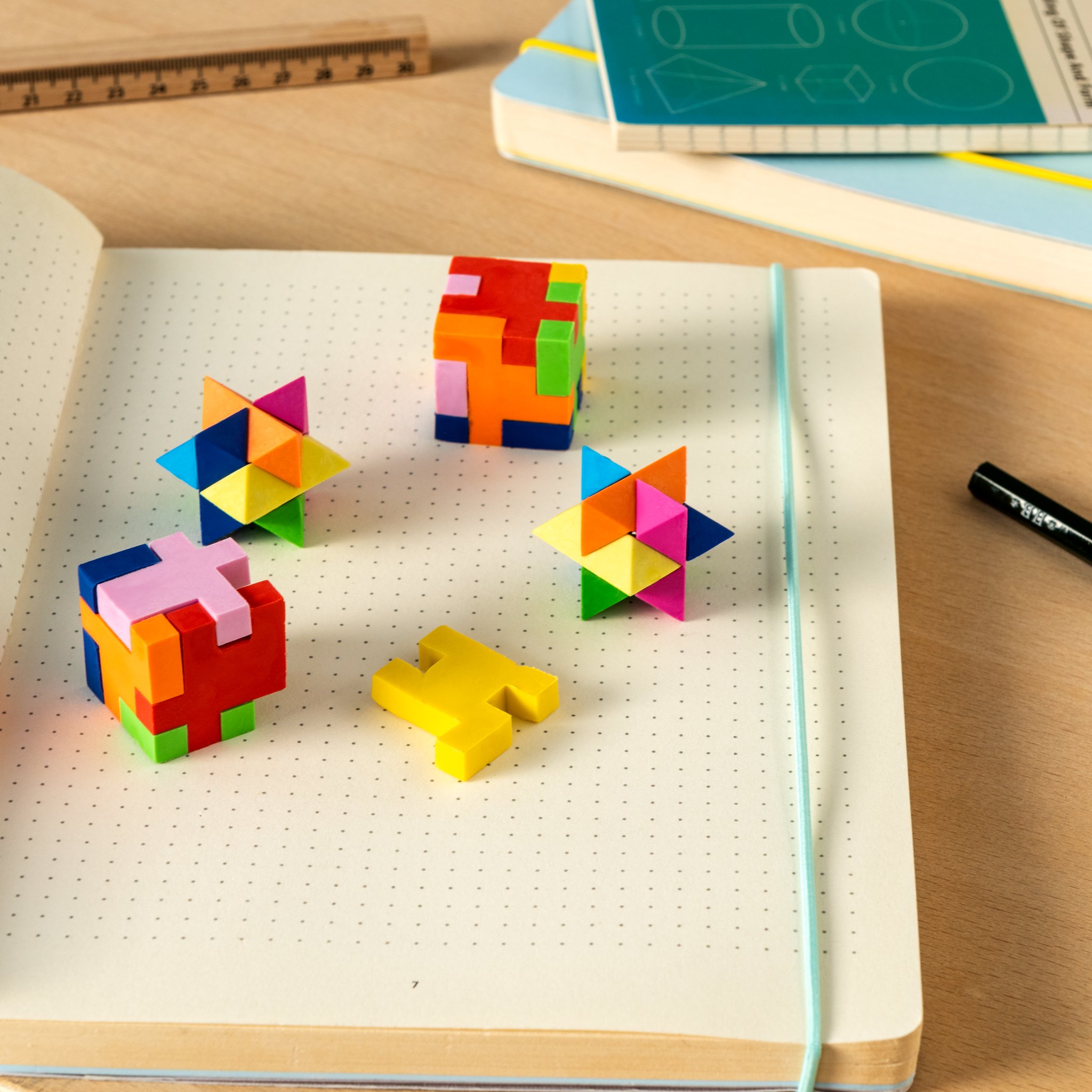 Gomme puzzle 3D a cubo e stella su un quaderno puntinato