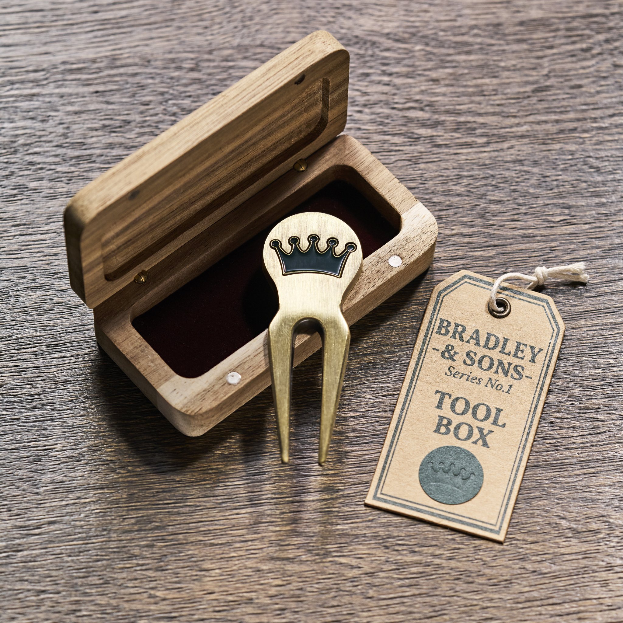 Messing-Divot-Tool mit Kronen-Emblem im aufgeklappten Hartholz-Etui mit Anhänger