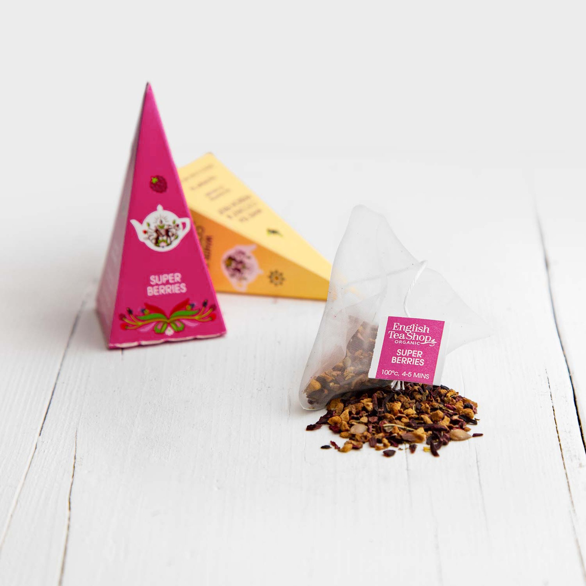 Bustina a piramide Super Berries con tè sfuso davanti alla piramide rosa abbinata
