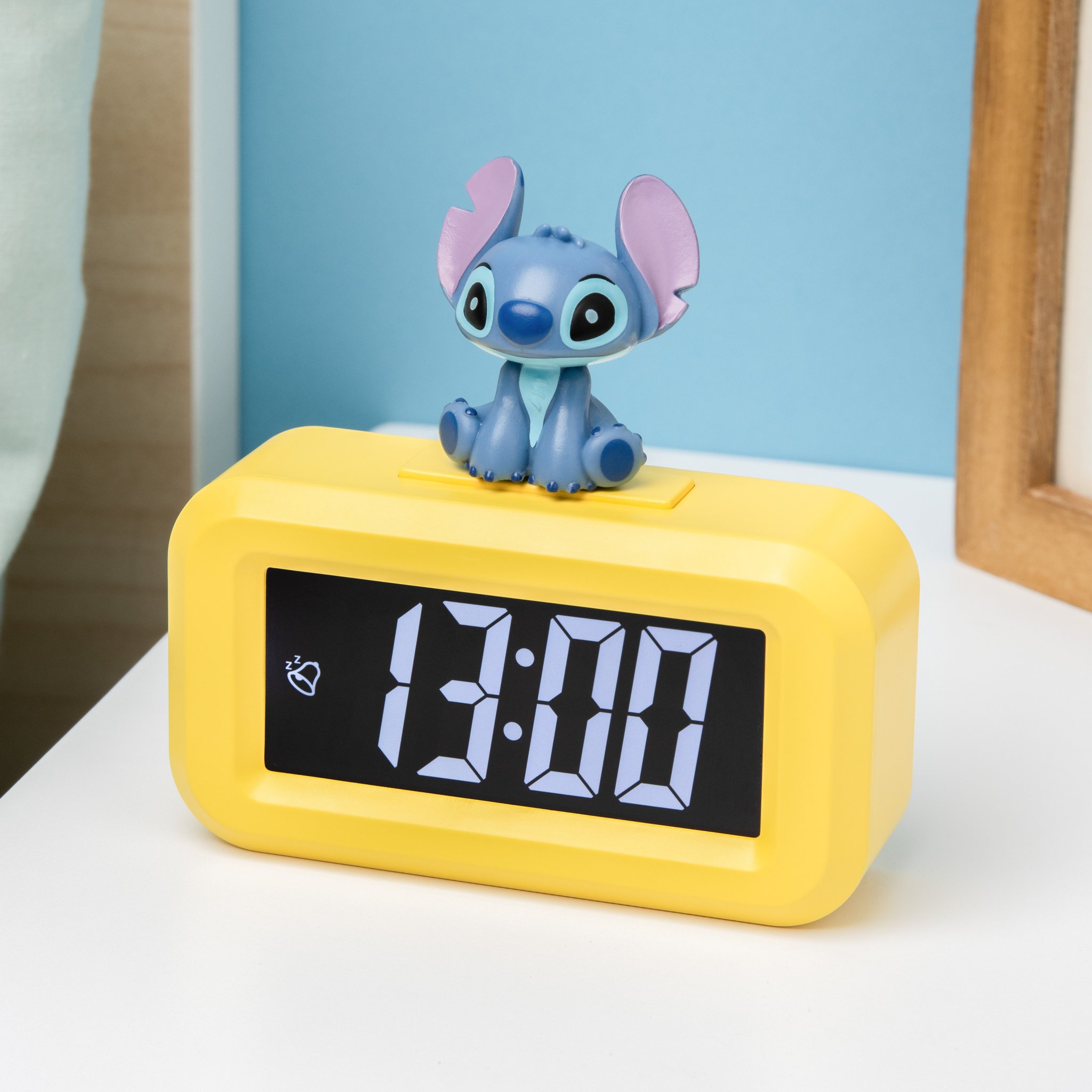 Stitch-Mini-Wecker auf einem Tisch vor blauer Wand