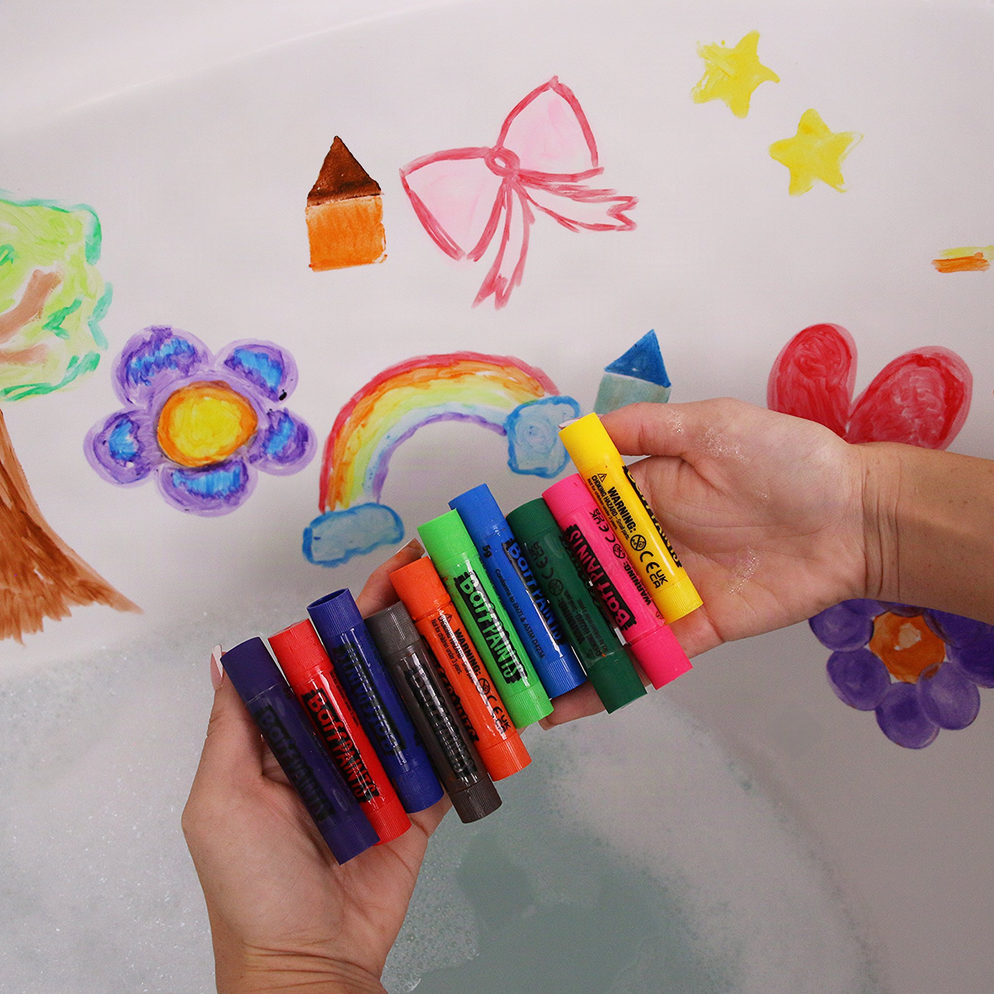 Hand holding all 10 Baff Paints sticks in front of a painted tub