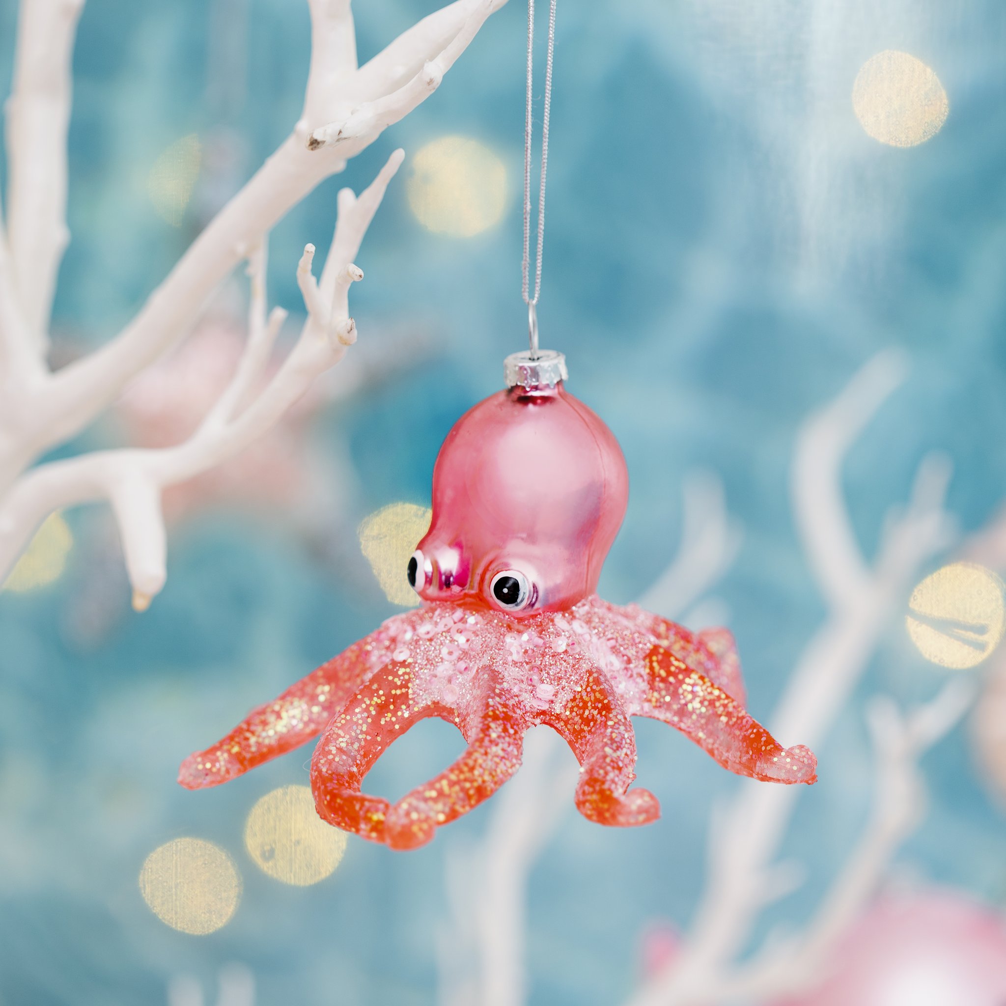 Sass & Belle octopus glitter bauble hanging from white coral branches with golden bokeh – lifestyle shot