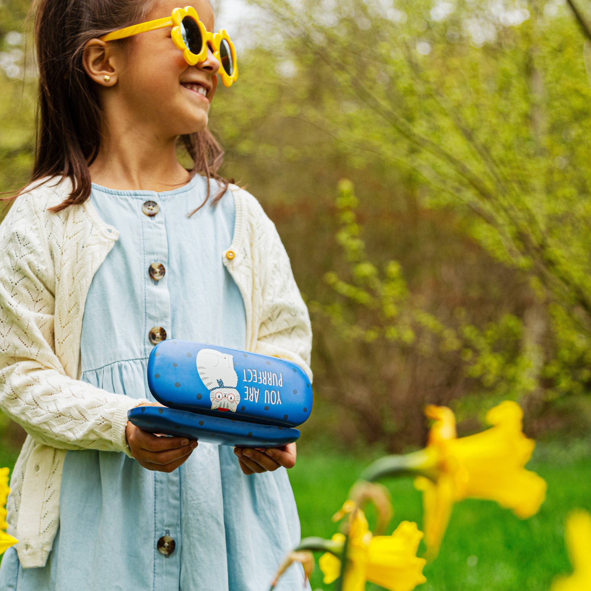 Girl with sunglasses holding the Purrfect cat glasses case in the garden