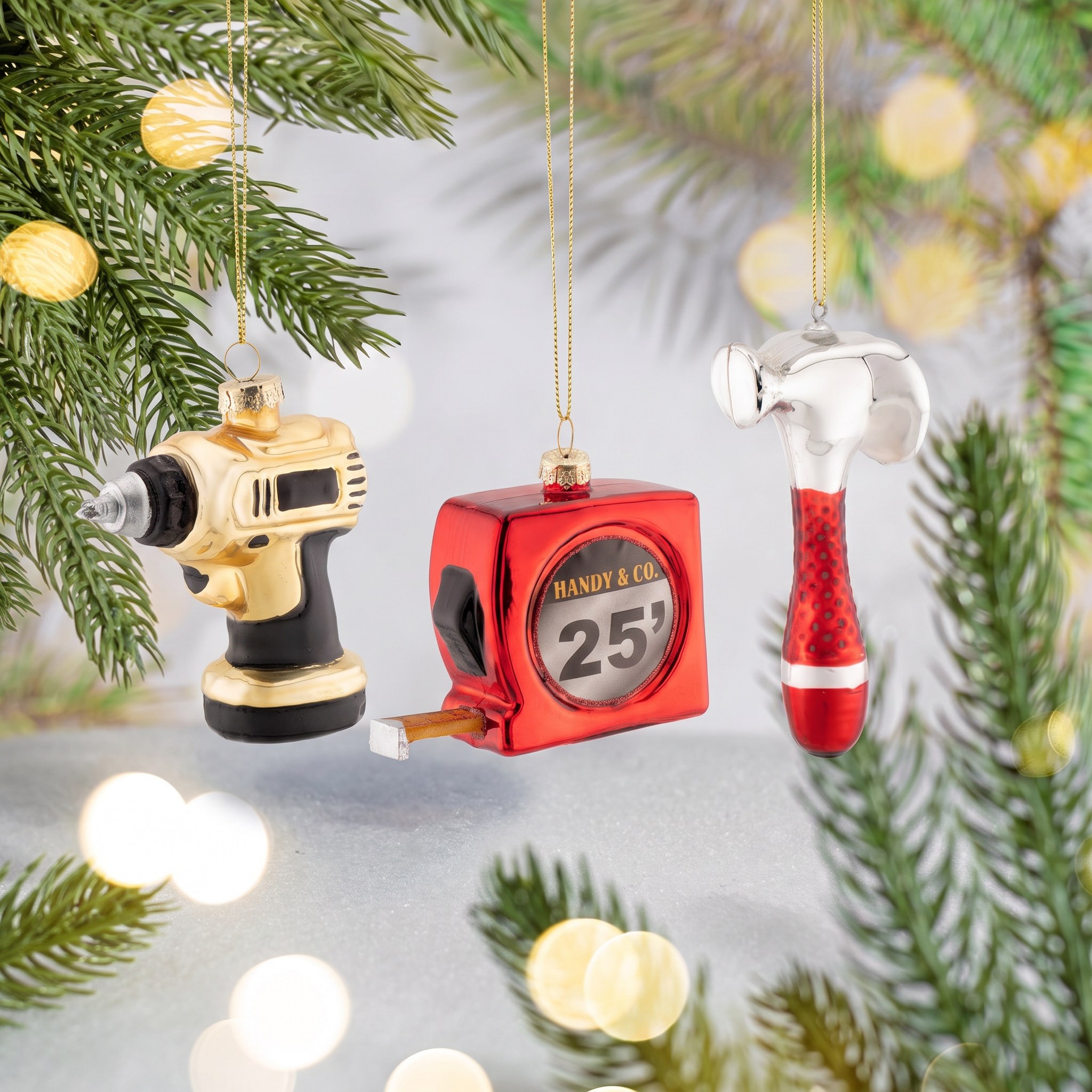 Tool-Shaped Christmas Baubles, Set of 3 by Sass & Belle on a fir branch with warm fairy lights