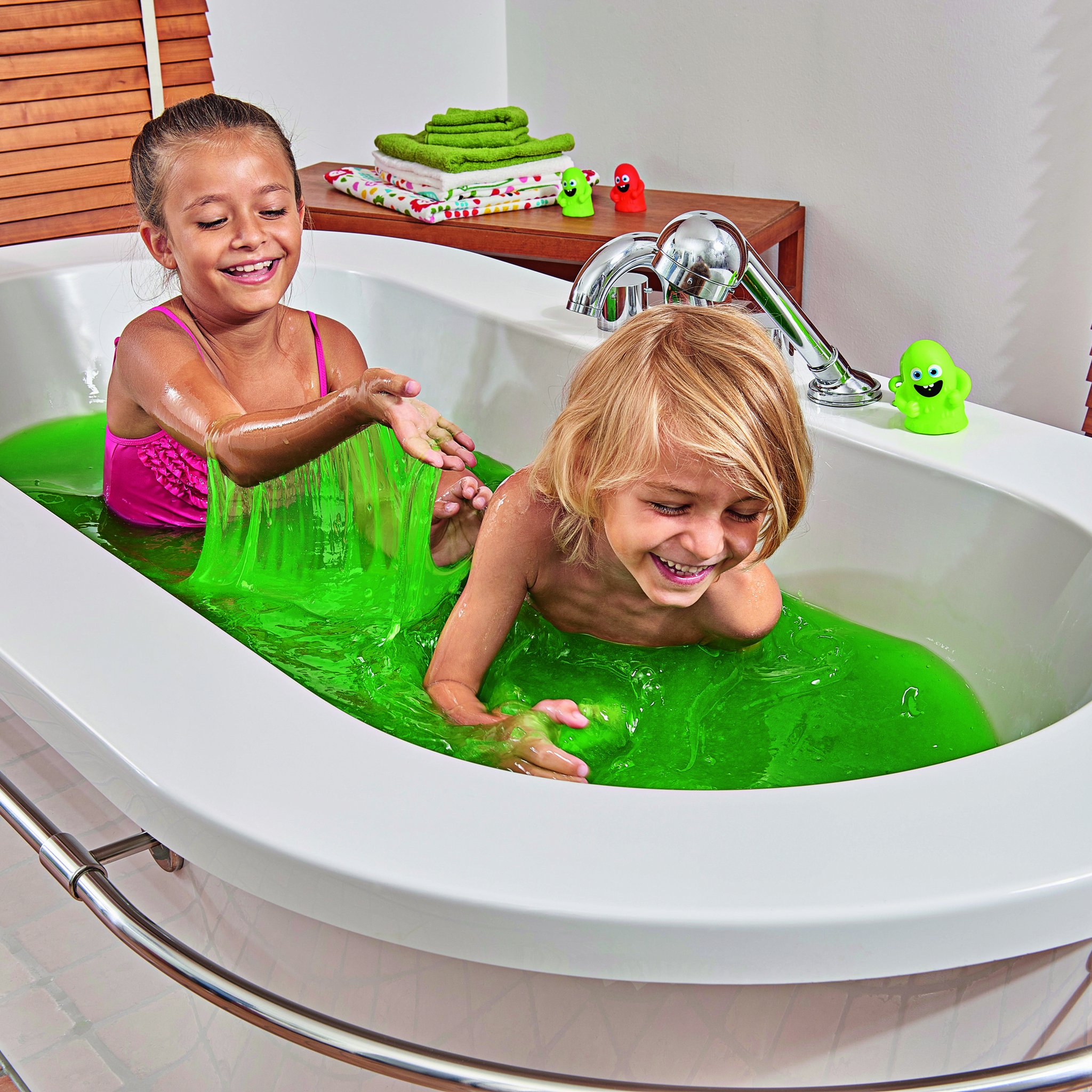 Two children playing in a bathtub full of green slime