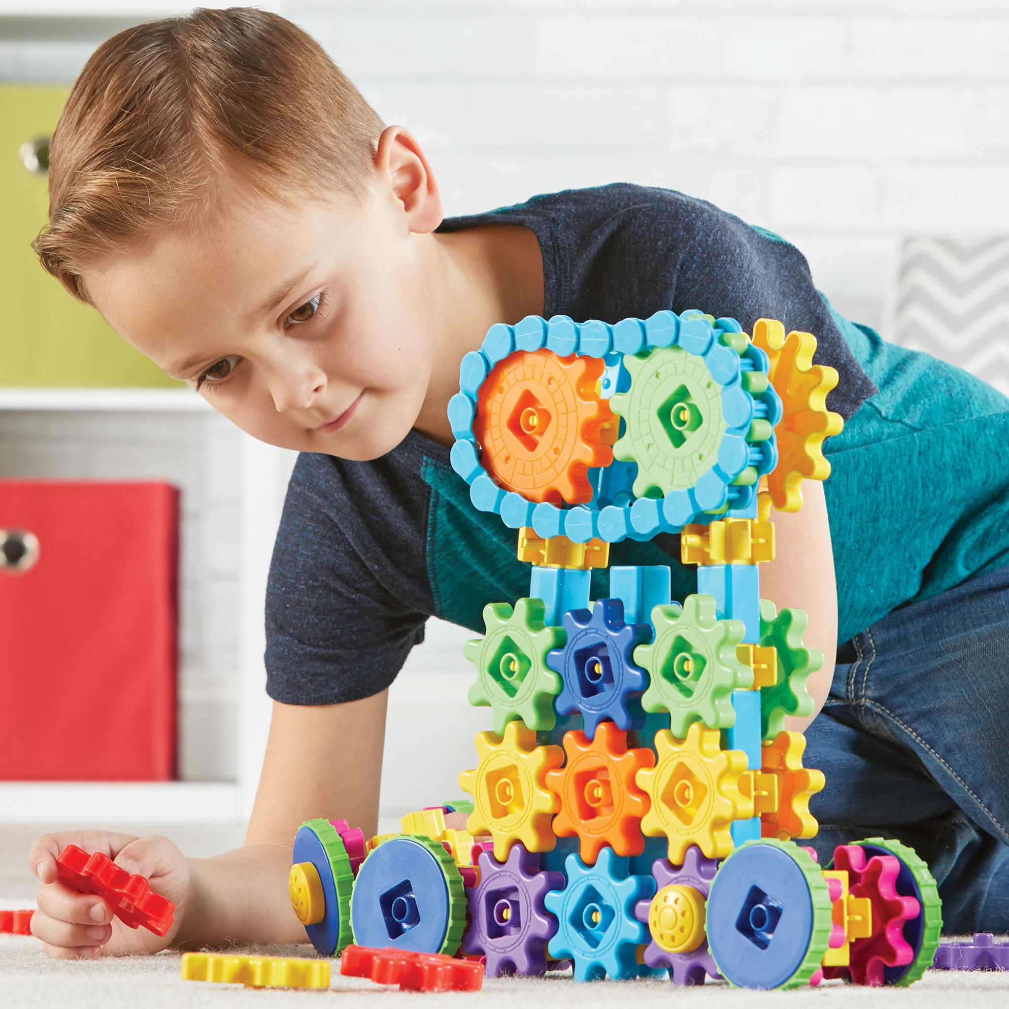 Junge dreht an den Zahnrädern seines Fahrzeugs aus dem Set Gears! Mega Builds