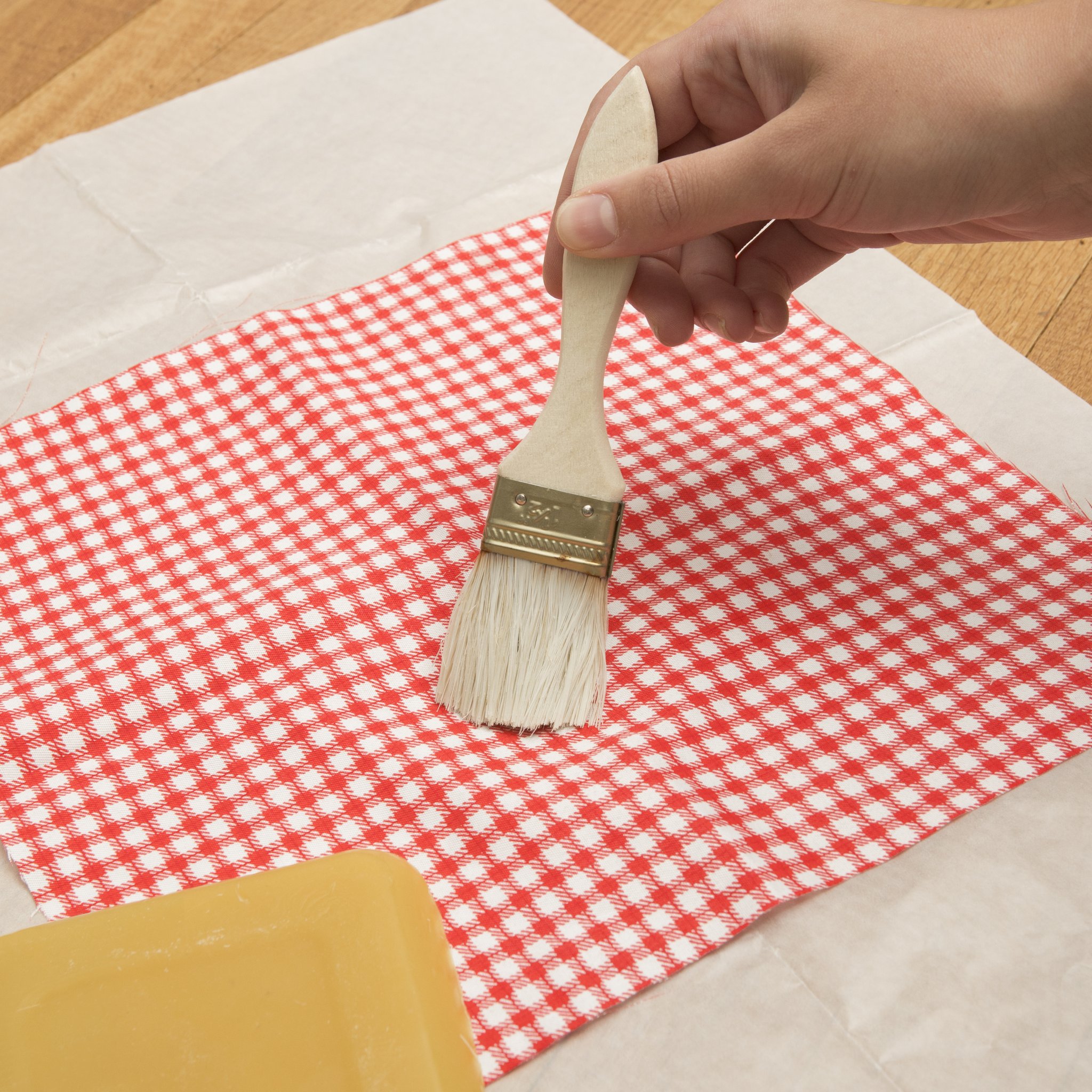 Pinceau appliquant la cire d'abeille sur le tissu à carreaux rouges