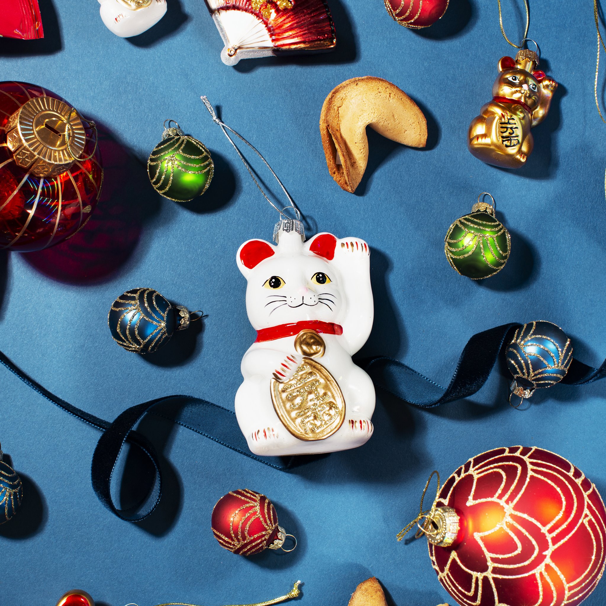 Décoration de sapin chat porte-bonheur Sass & Belle parmi des boules en verre sur fond bleu