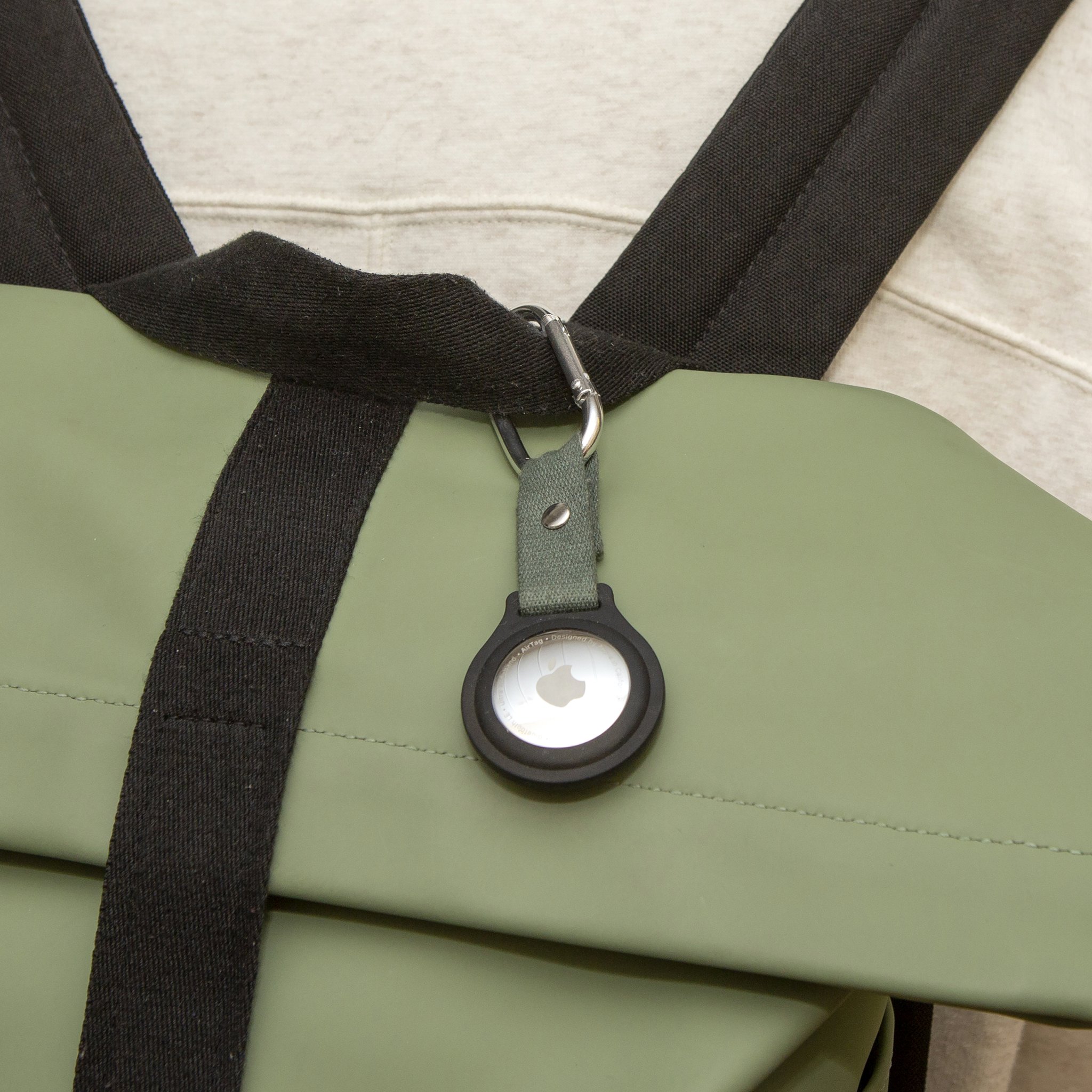 AirTag-Halter mit Karabiner am Gurt einer grünen Tasche