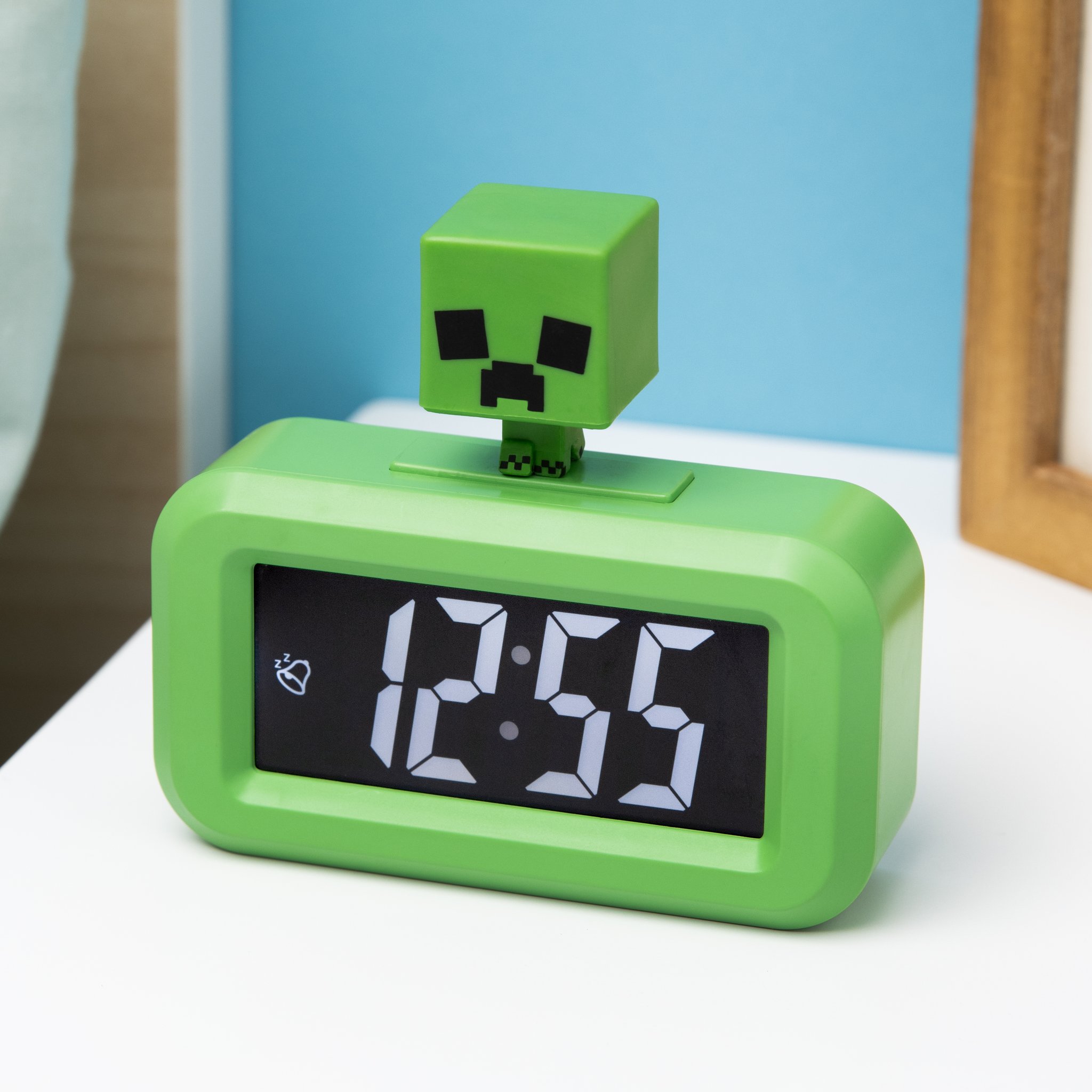 Creeper-Mini-Wecker auf einem Tisch vor blauer Wand