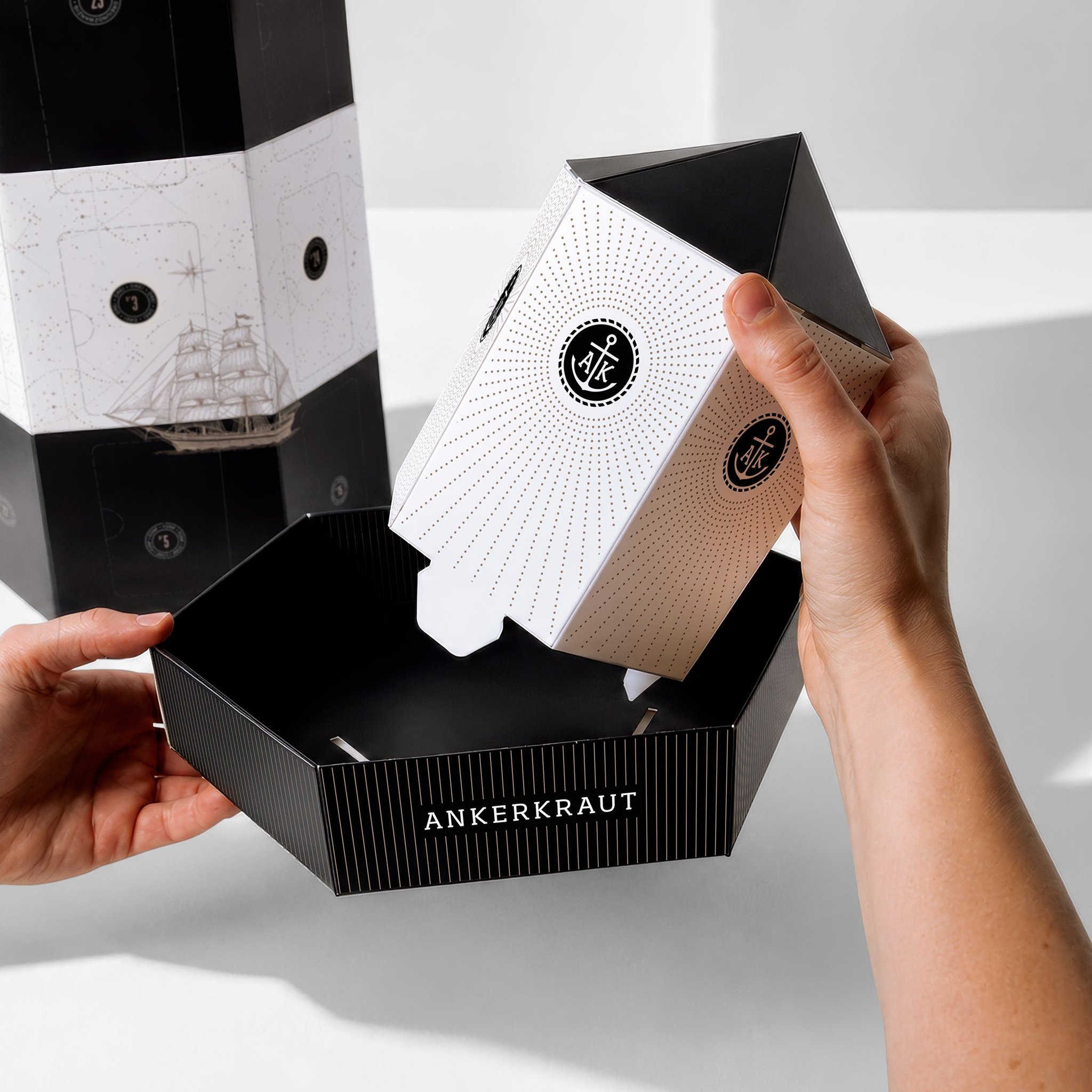 Aufbau des Leuchtturm-Adventskalenders: Hände öffnen das Dach mit Anker-Logo