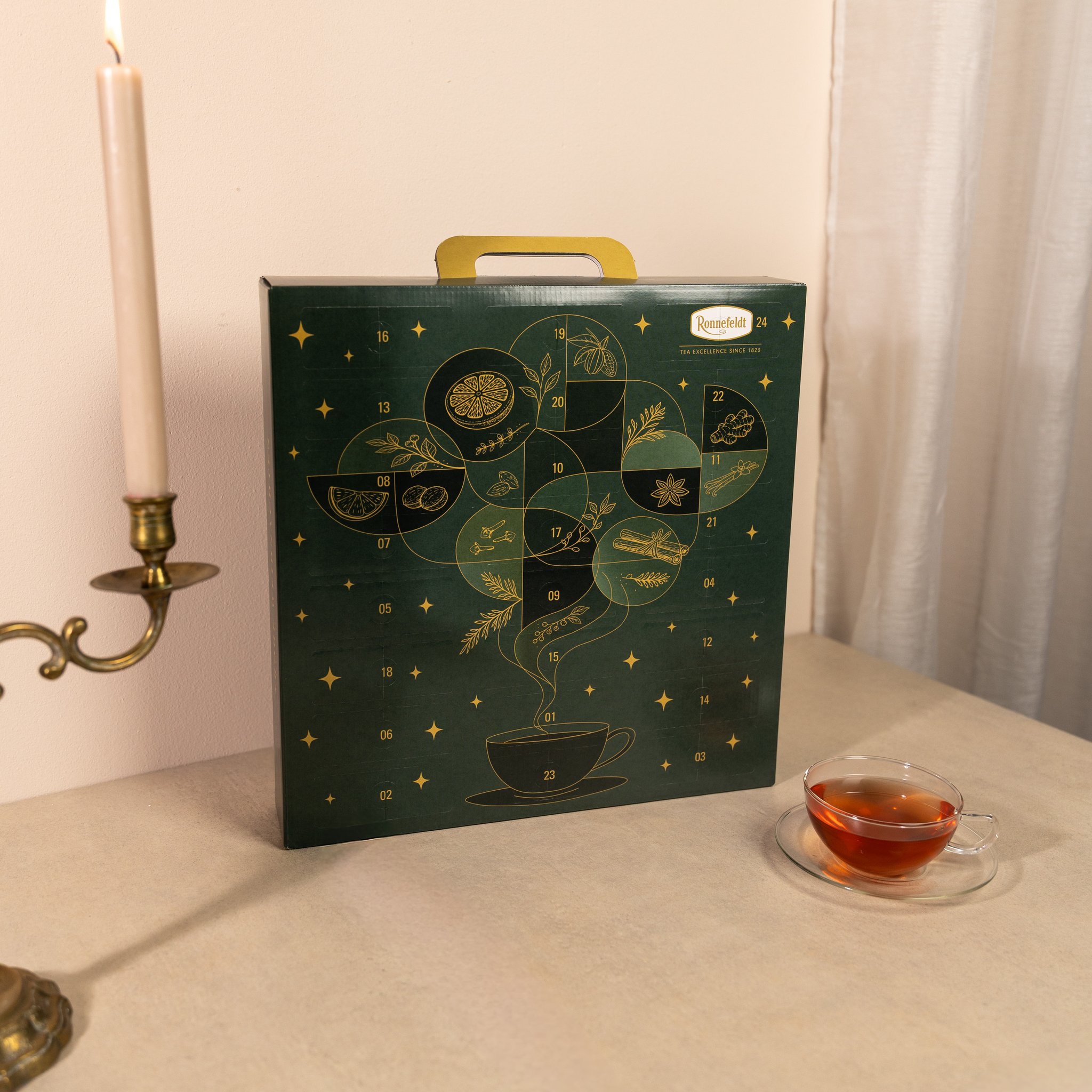 Calendrier de l'Avent thé sur une table à côté d'une bougie et d'une tasse de thé
