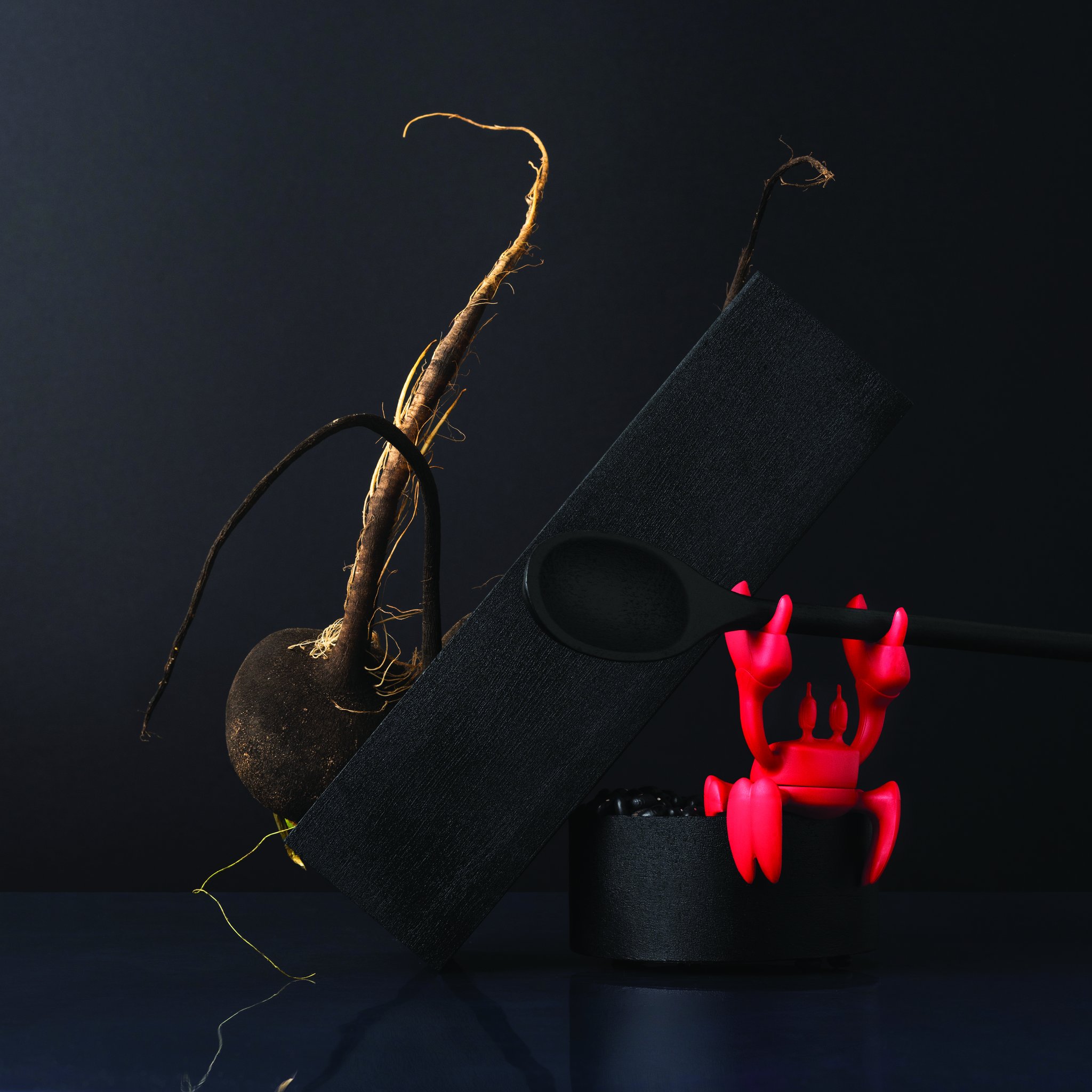 Red crab holding a wooden spoon beside beets and root vegetables