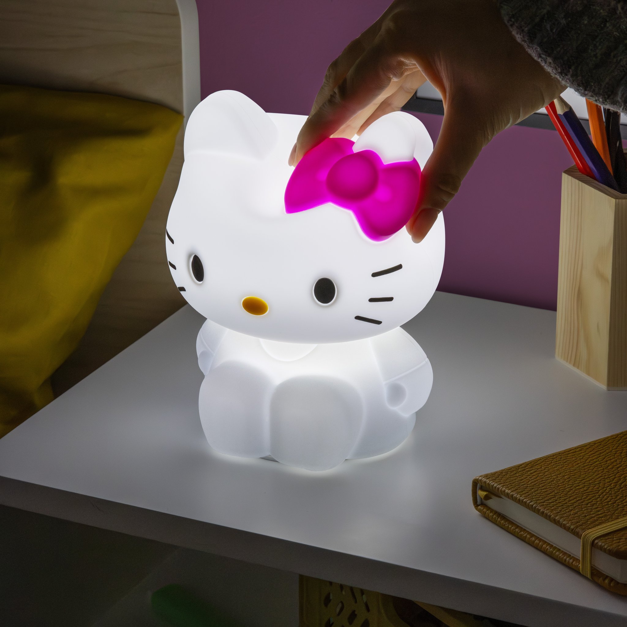 Hand tippt auf den Kopf des Hello-Kitty-Nachtlichts