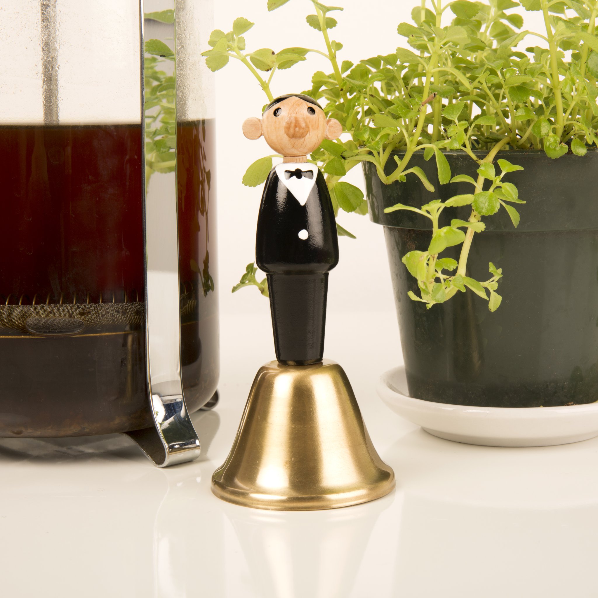 Cloche de table serveur à côté d'une cafetière et d'un pot d'herbes