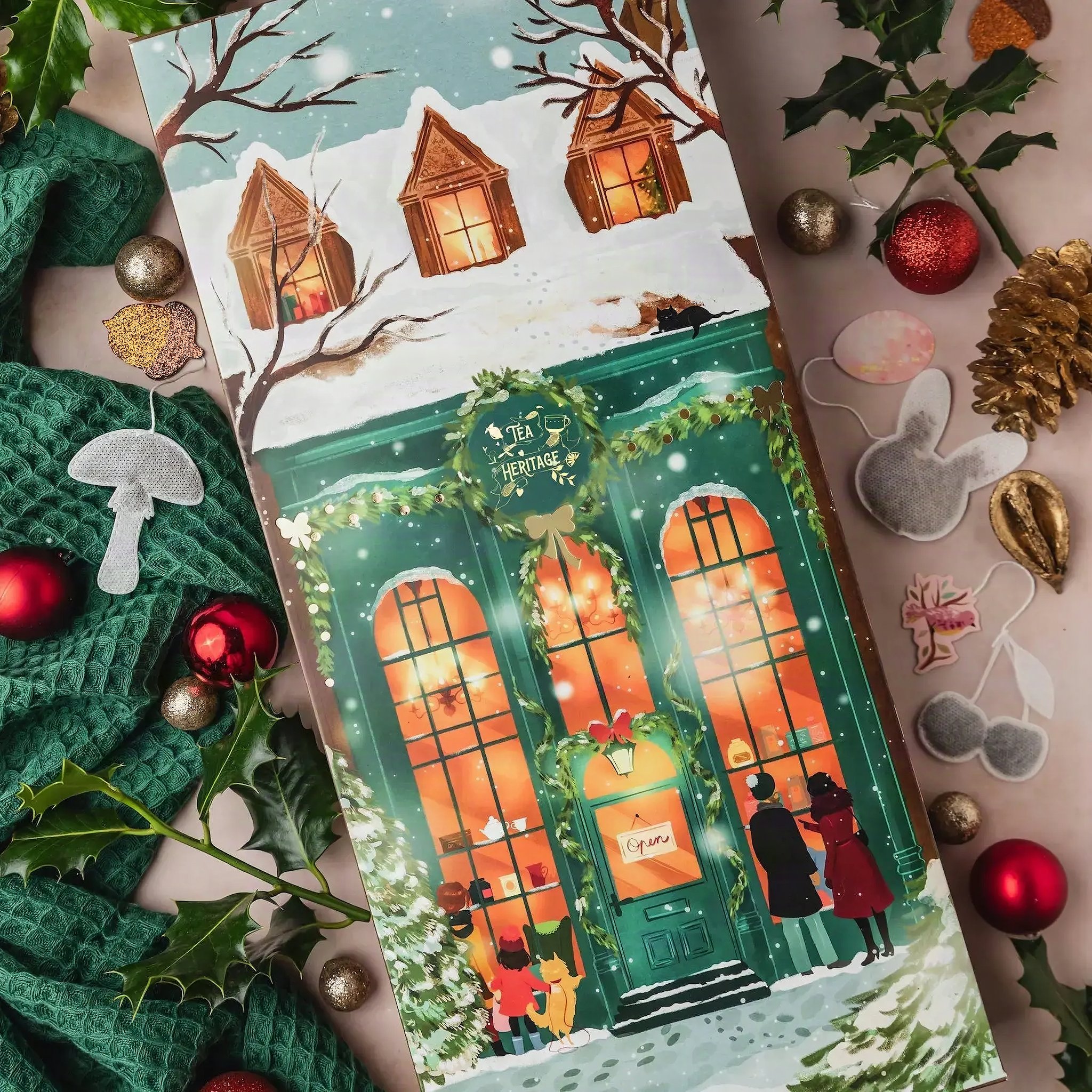 Calendario dell'Avvento di tè Mon Petit Chalet con negozio illustrato e chalet innevati su maglia verde