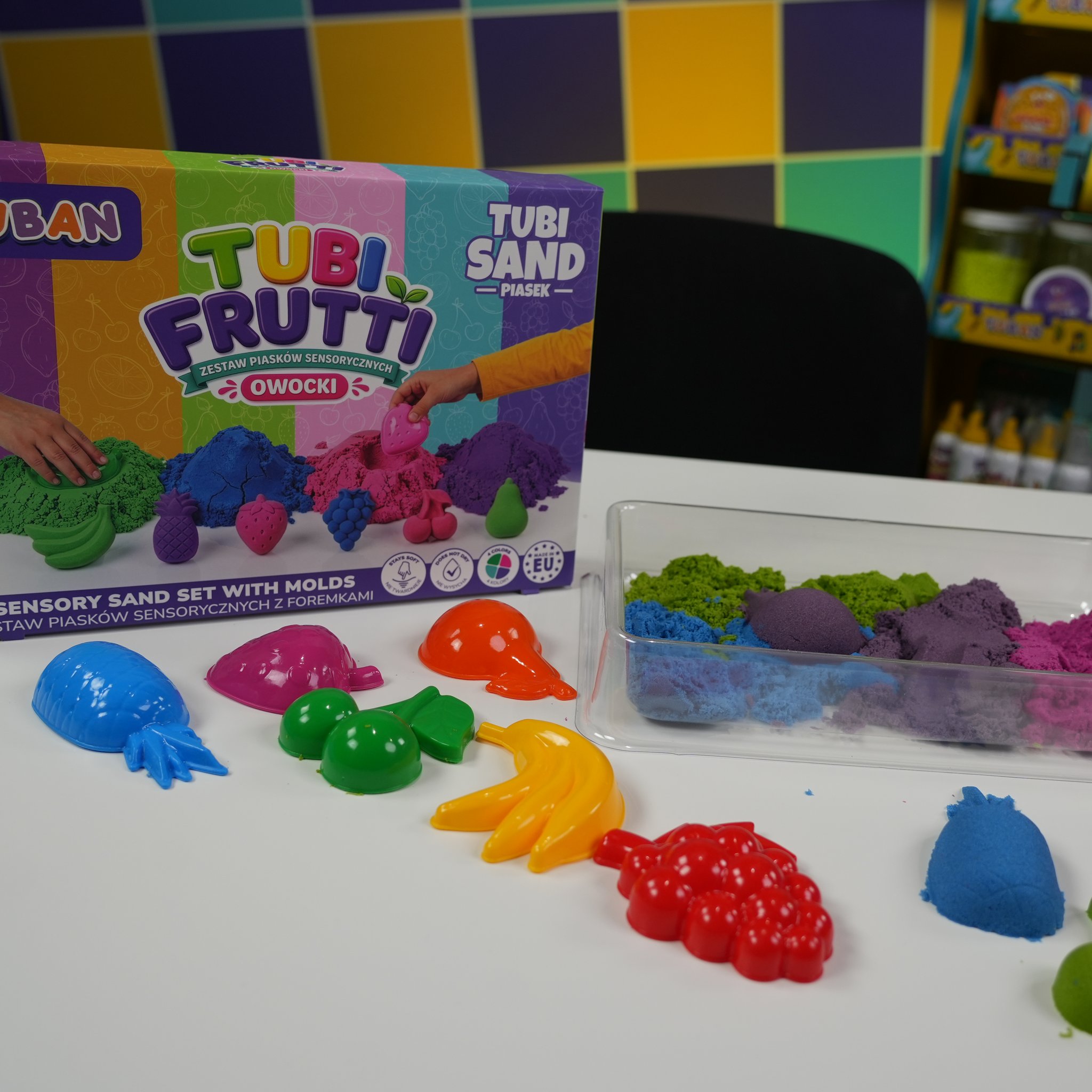Formine a frutta colorate davanti alla vaschetta di sabbia sensoriale modellata