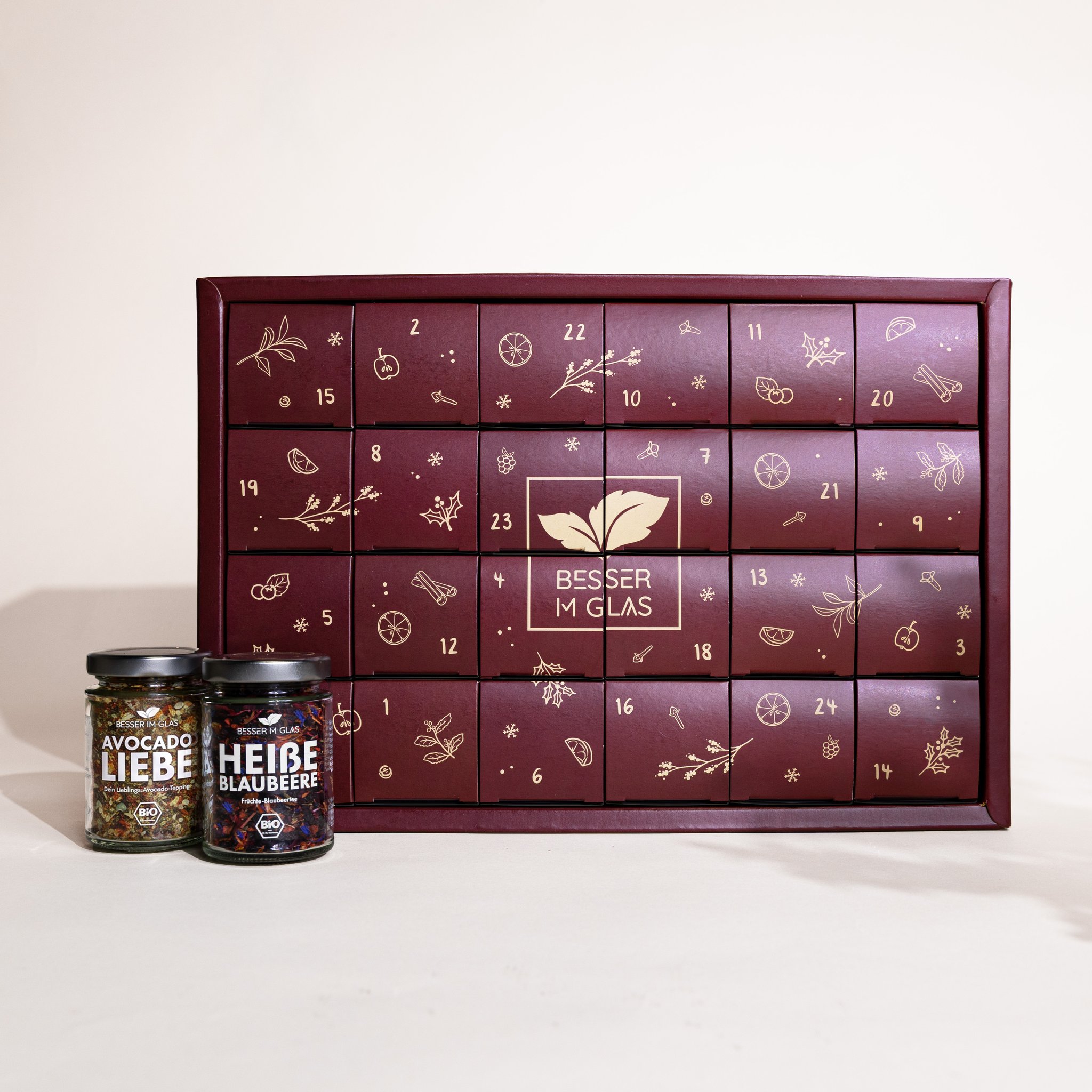 Bordeauxroter Bio Tee- und Gewürz-Adventskalender von Besser im Glas, daneben Gewürz- und Teeglas