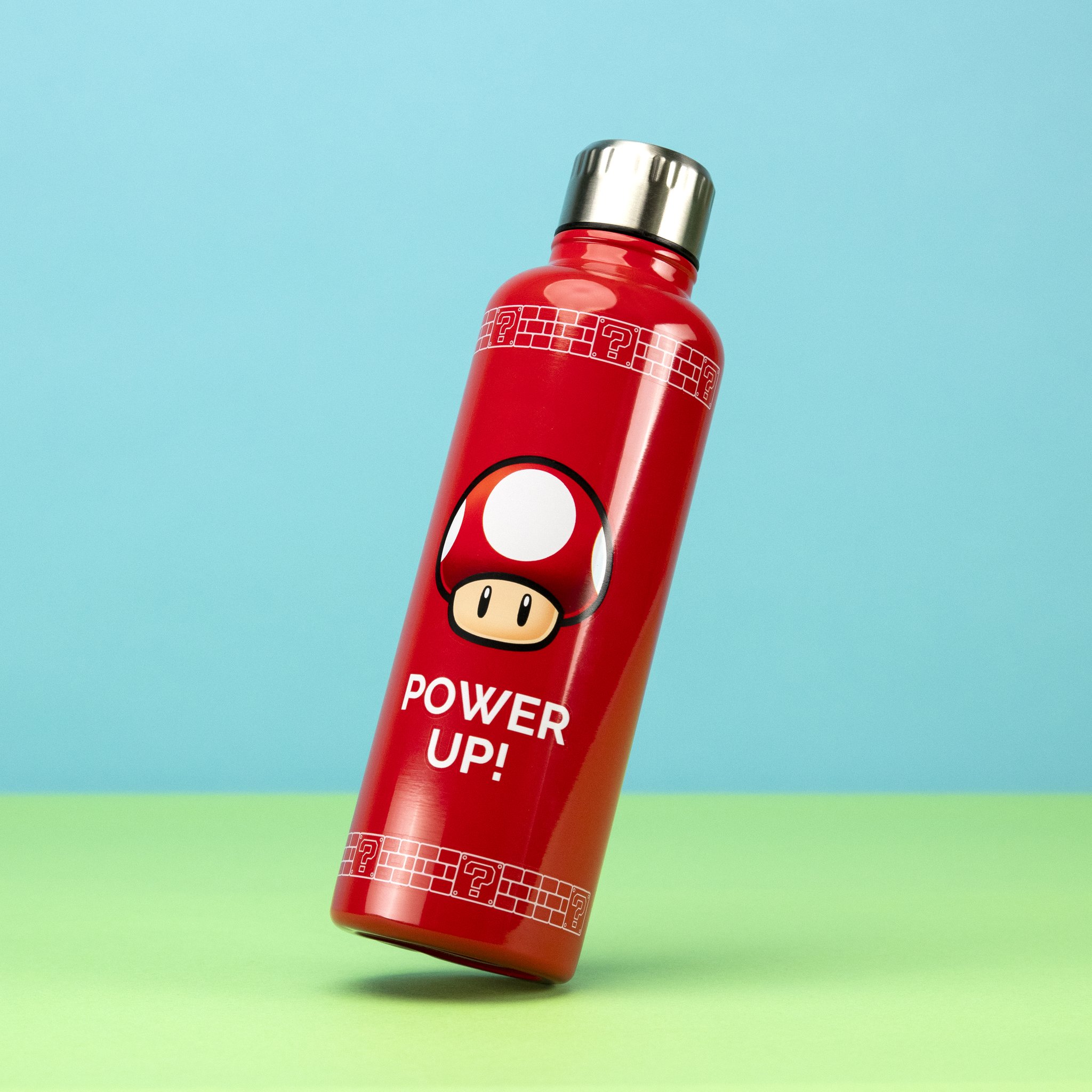 Rote Super-Mario-Trinkflasche mit Power-Up-Pilz vor blau-grünem Hintergrund