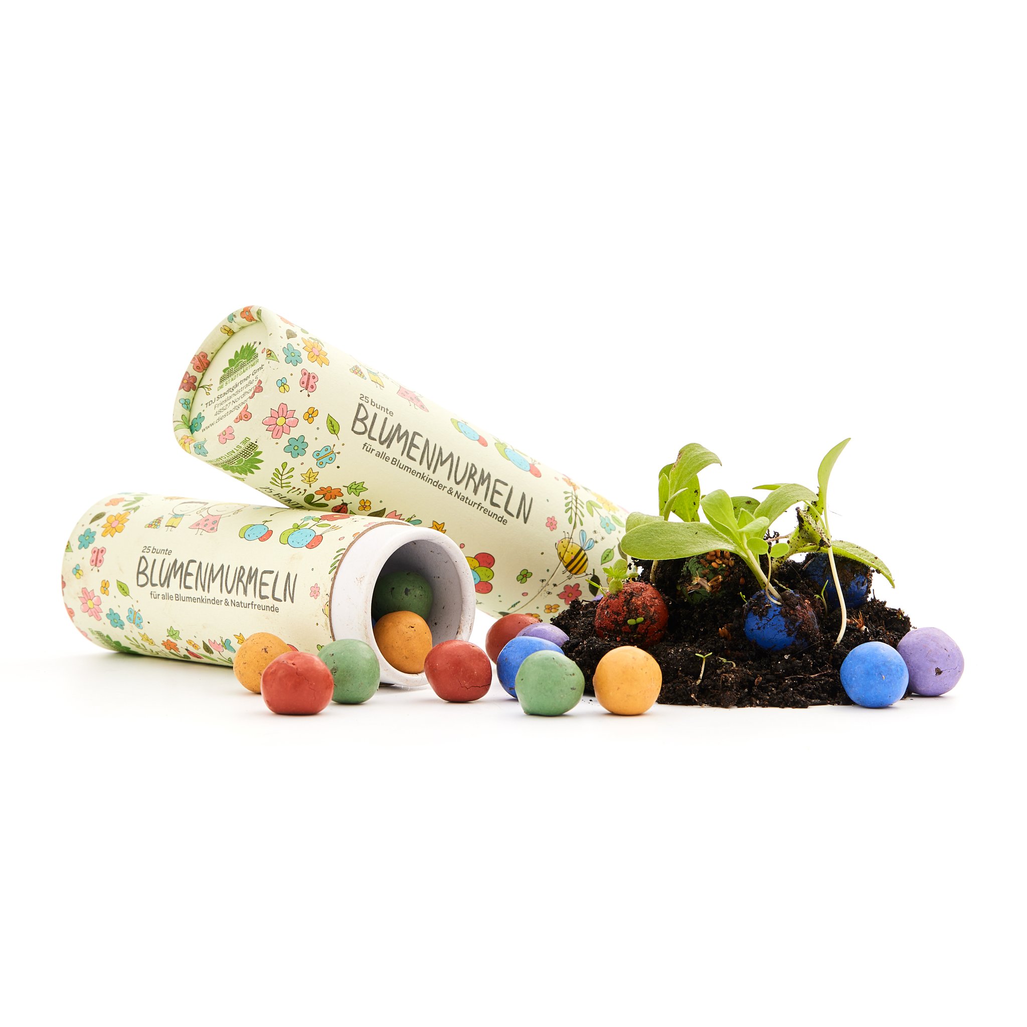 Dosen mit Blumenmurmeln auf weissem Grund, bunte Seedbombs neben Erde und jungen Pflanzen