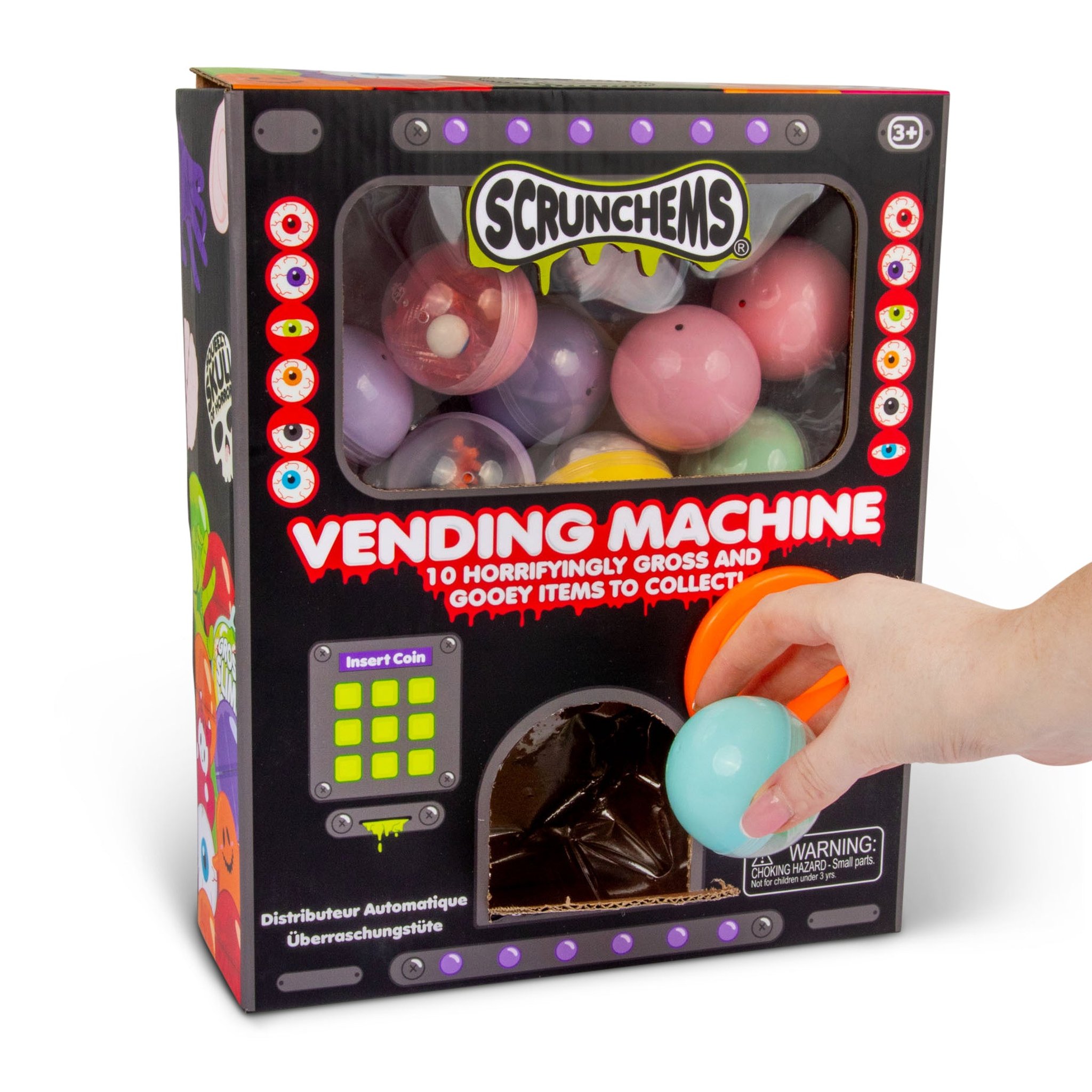 Main d'enfant qui prend une capsule turquoise dans la Horror Vending Machine de Scrunchems