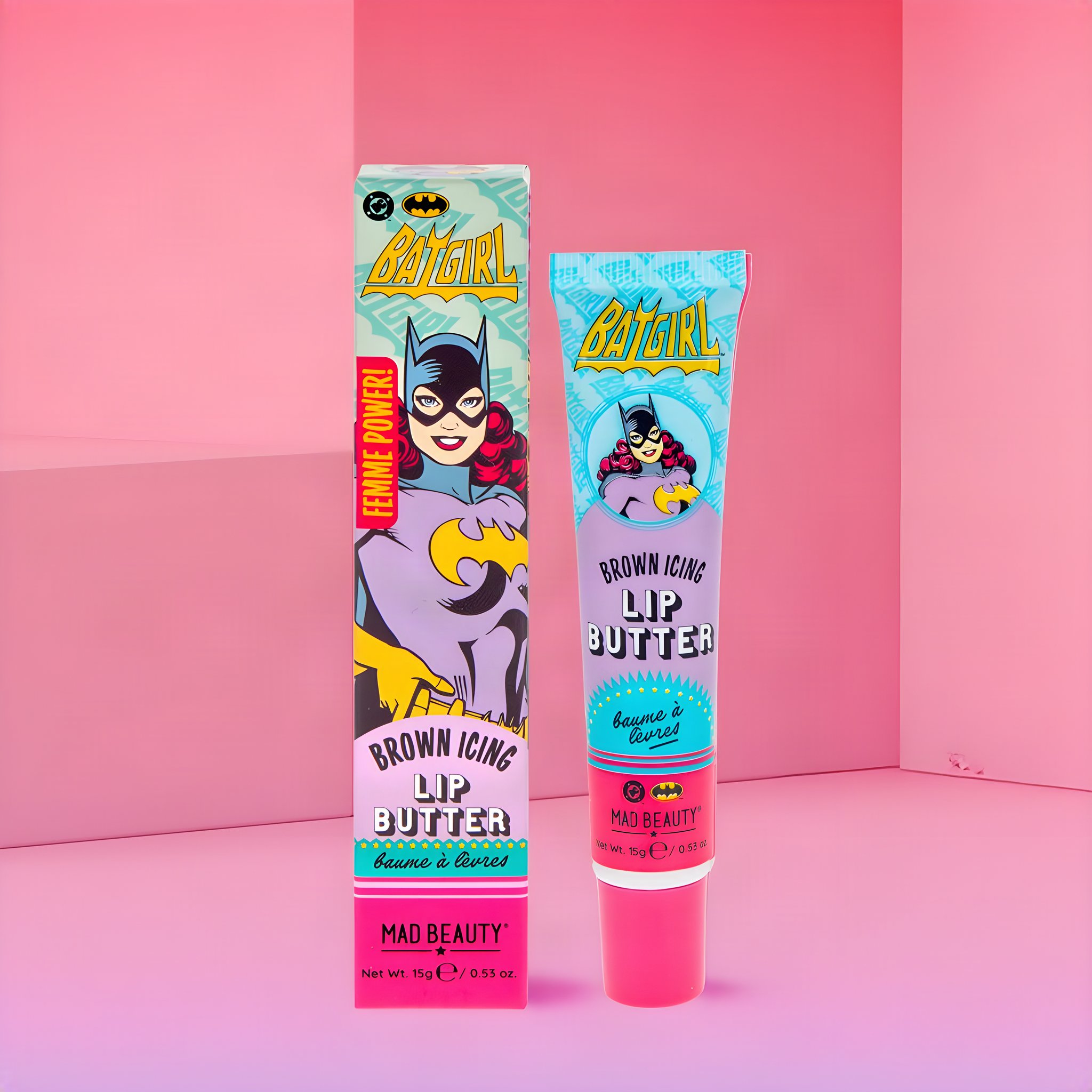Batgirl Lip Butter: pinke Tube neben der Faltschachtel mit Comic-Batgirl, inszeniert in einem rosa Raum