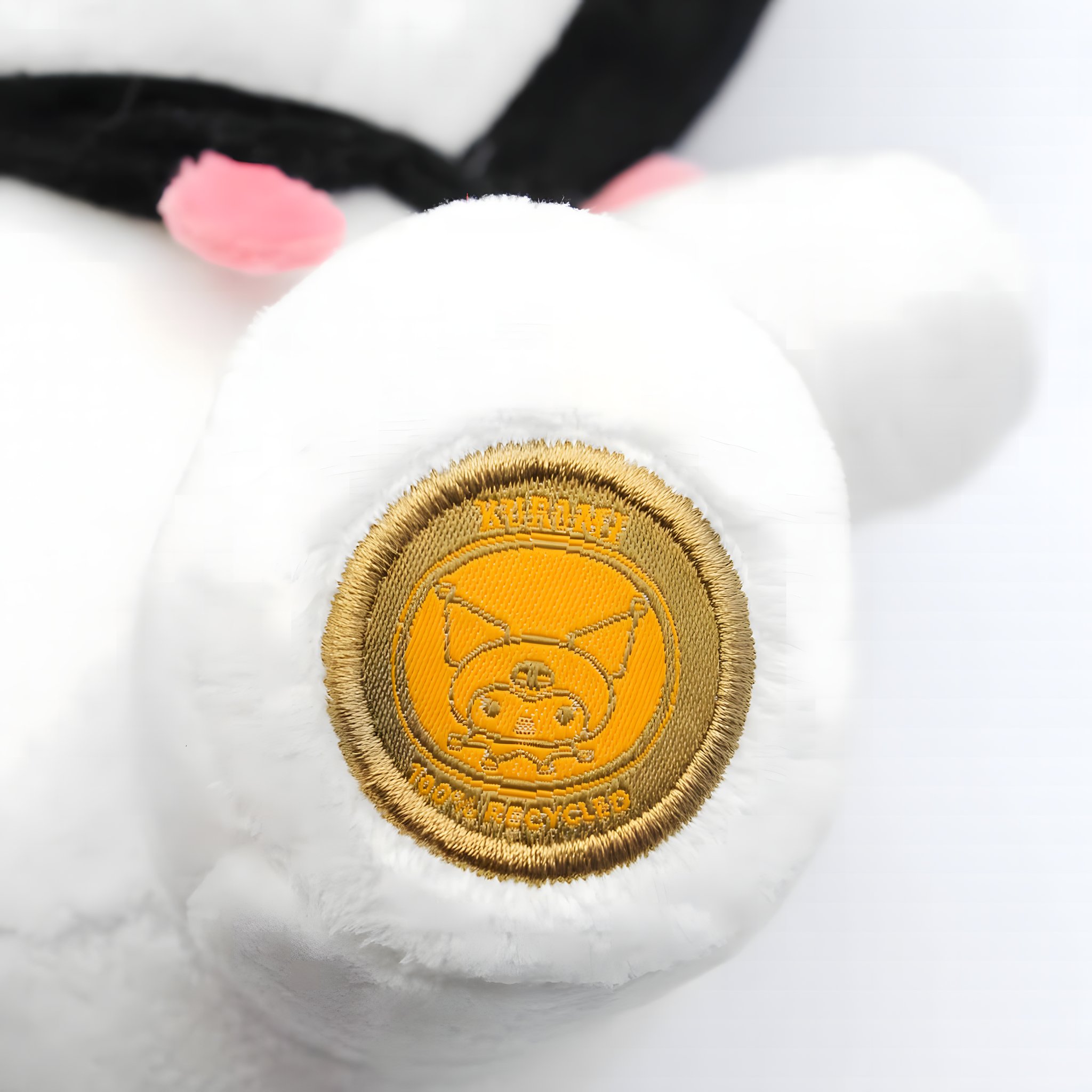 Detail des gestickten goldenen Sanrio-Echtheitsetiketts am Fuss der Kuromi Plüschfigur