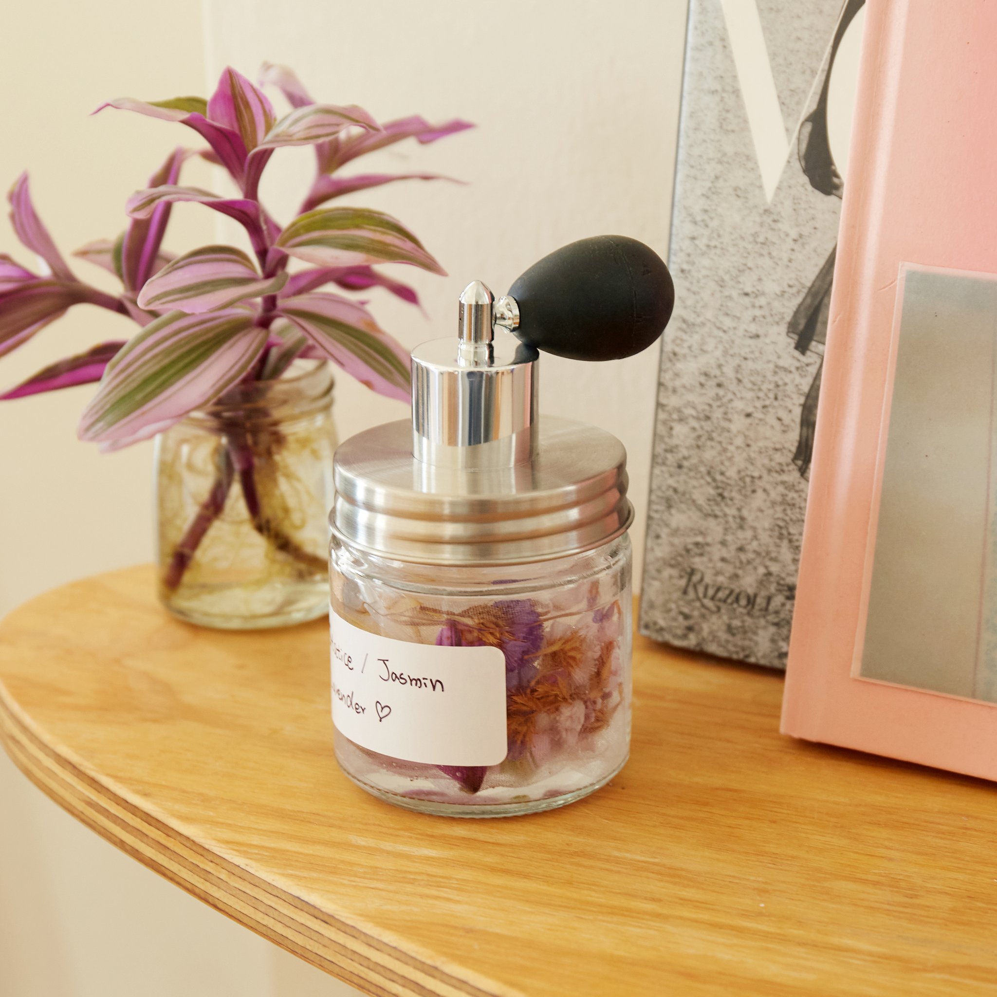 Vaporisateur de parfum avec fleurs séchées sur une étagère en bois près d'une plante