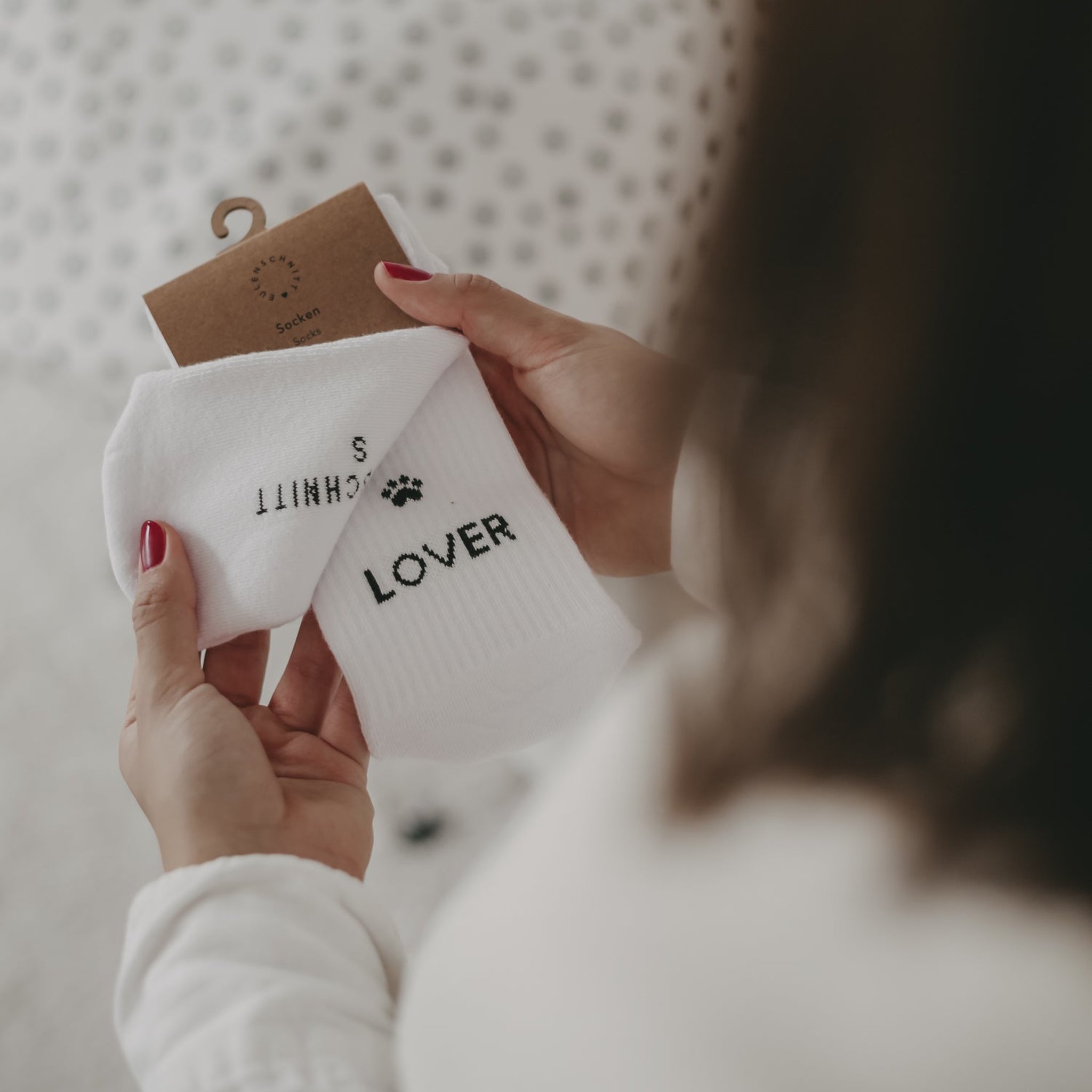 Detail der weissen Socke mit Pfote und Schriftzug LOVER in den Händen