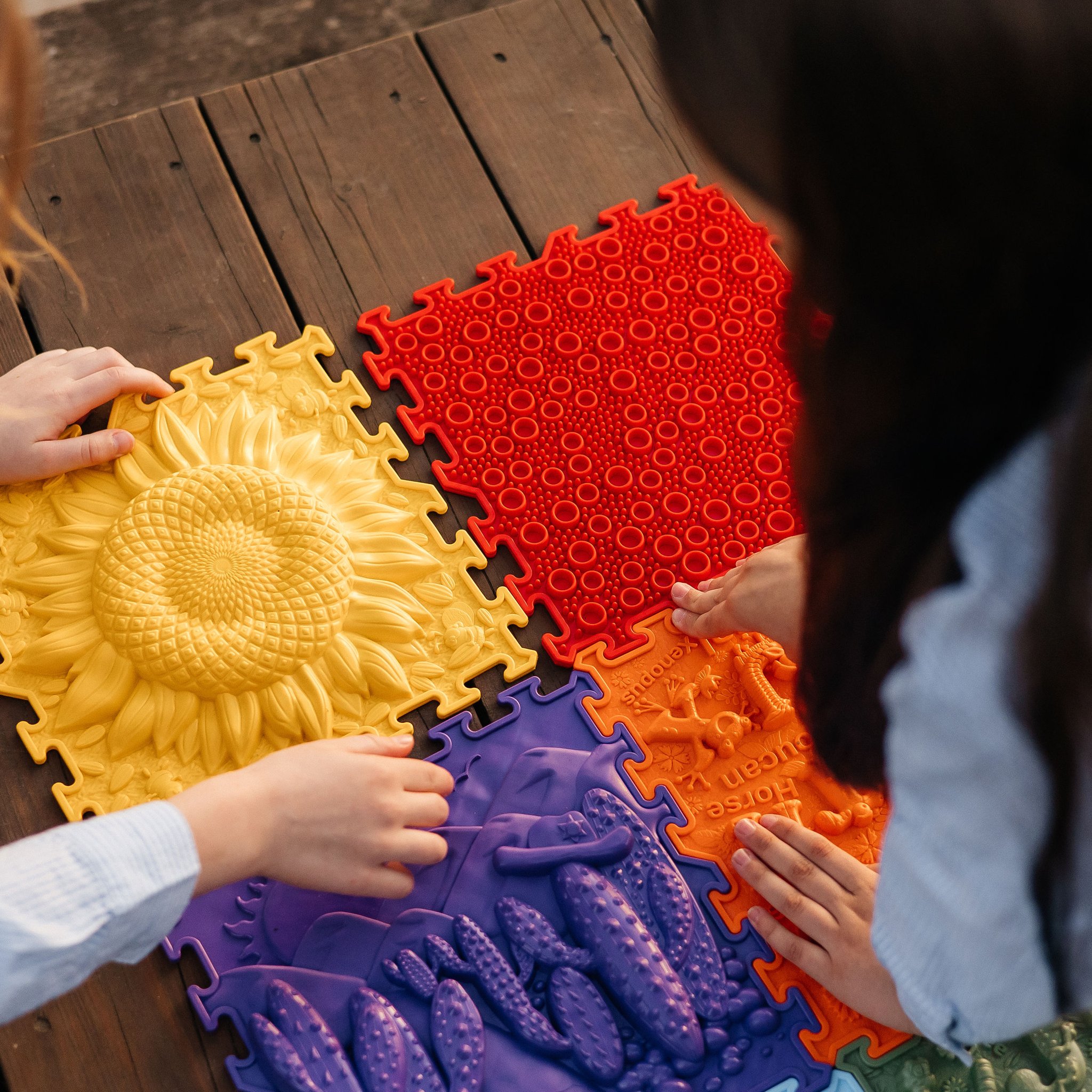 Kinderhände tasten die Sonnenblumenkachel und die Reliefs der Sensorikmatten ab