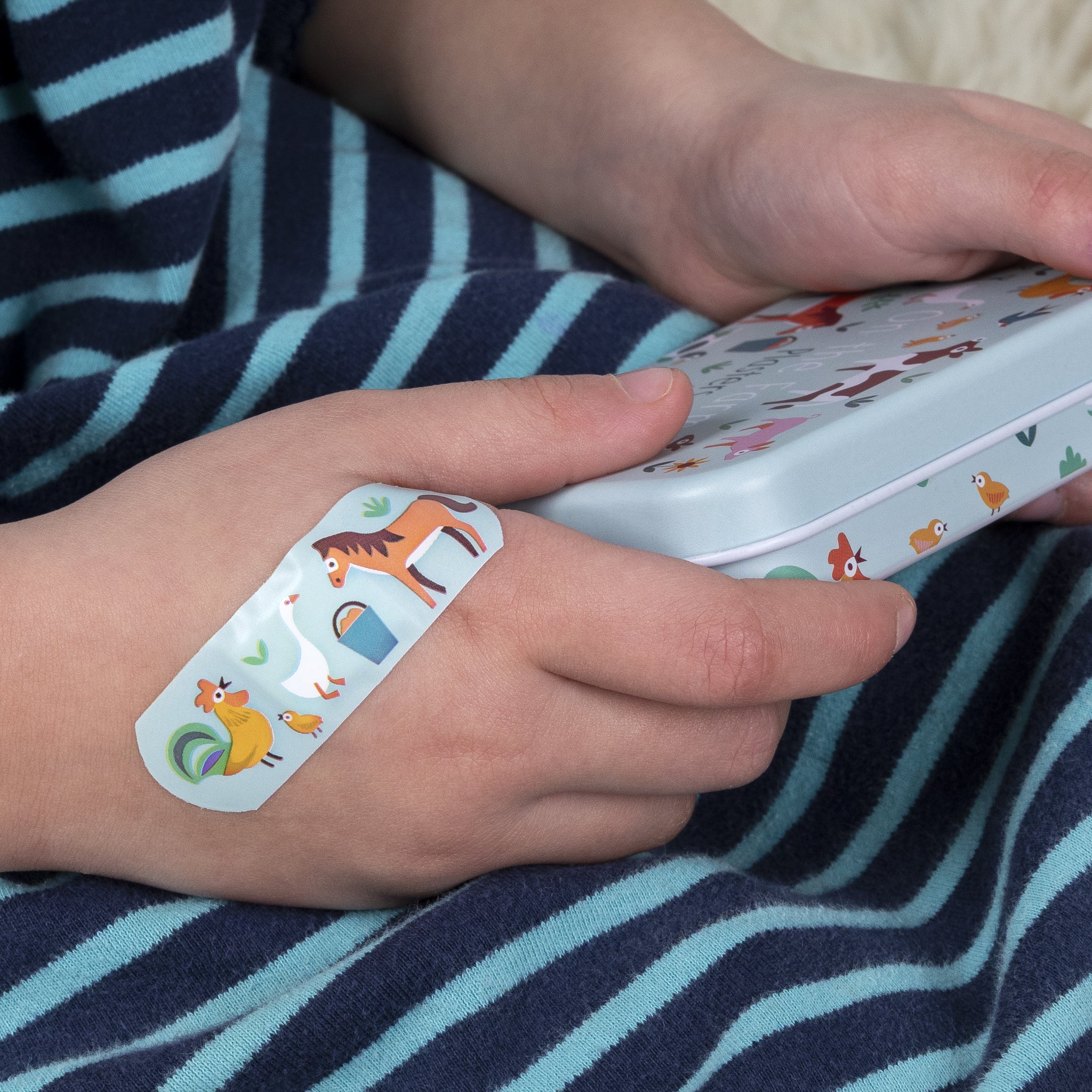Farm children's plaster on the back of a child's hand, tin beside it