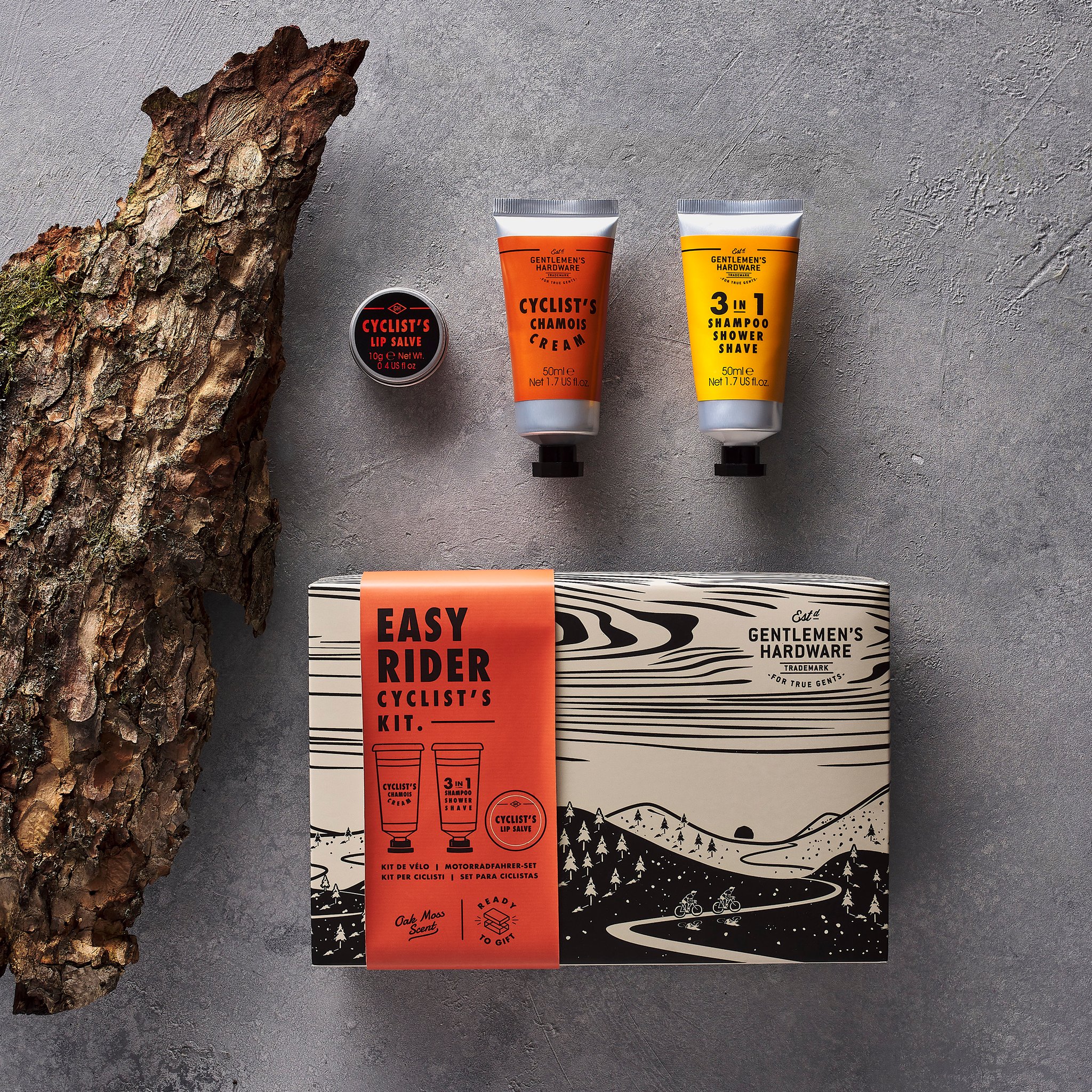 Coffret Easy Rider sur fond gris, tubes et baume à lèvres au-dessus de la boîte, avec un morceau d'écorce à gauche