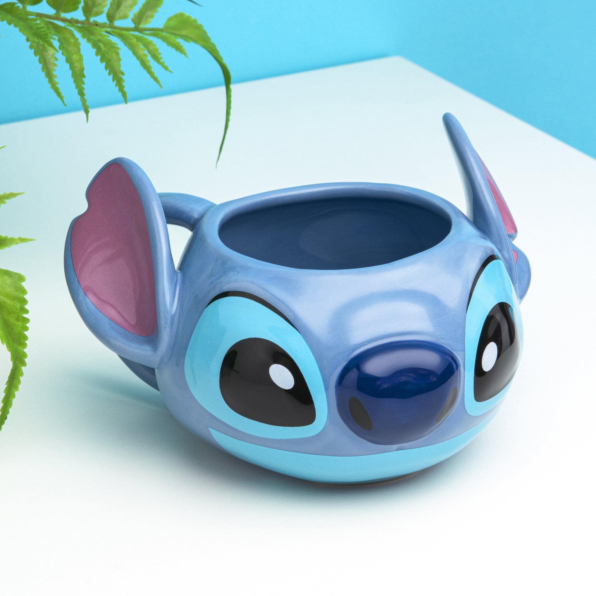 3D mug shaped like Stitch's head with pointed ears on a light blue table