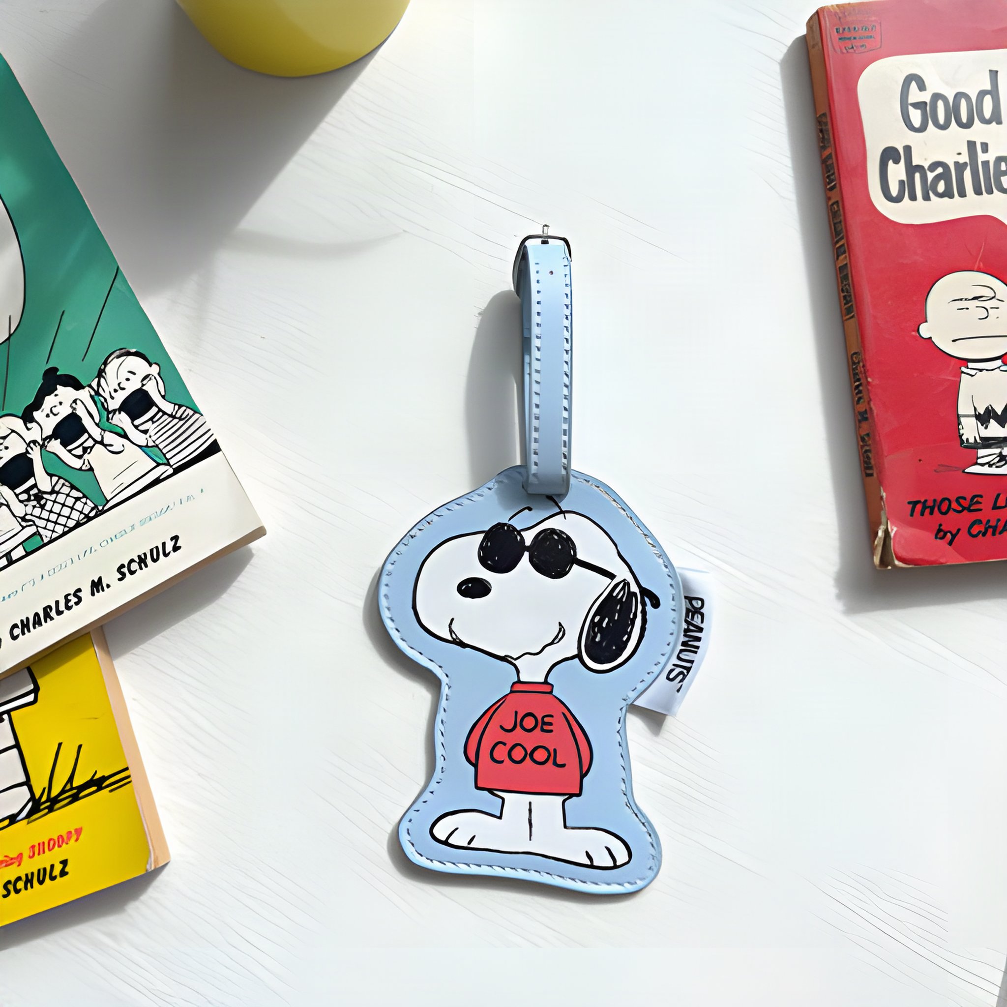 Snoopy Joe Cool luggage tag next to Peanuts books