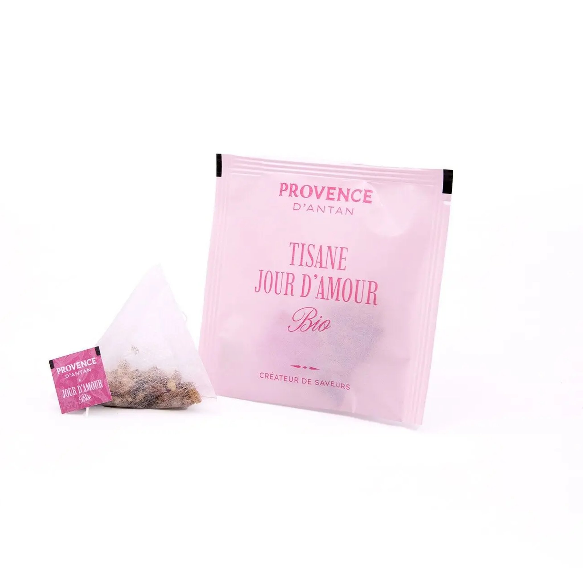 Pyramid bag with coarsely cut herbs in front of the pink envelope of the organic herbal tea