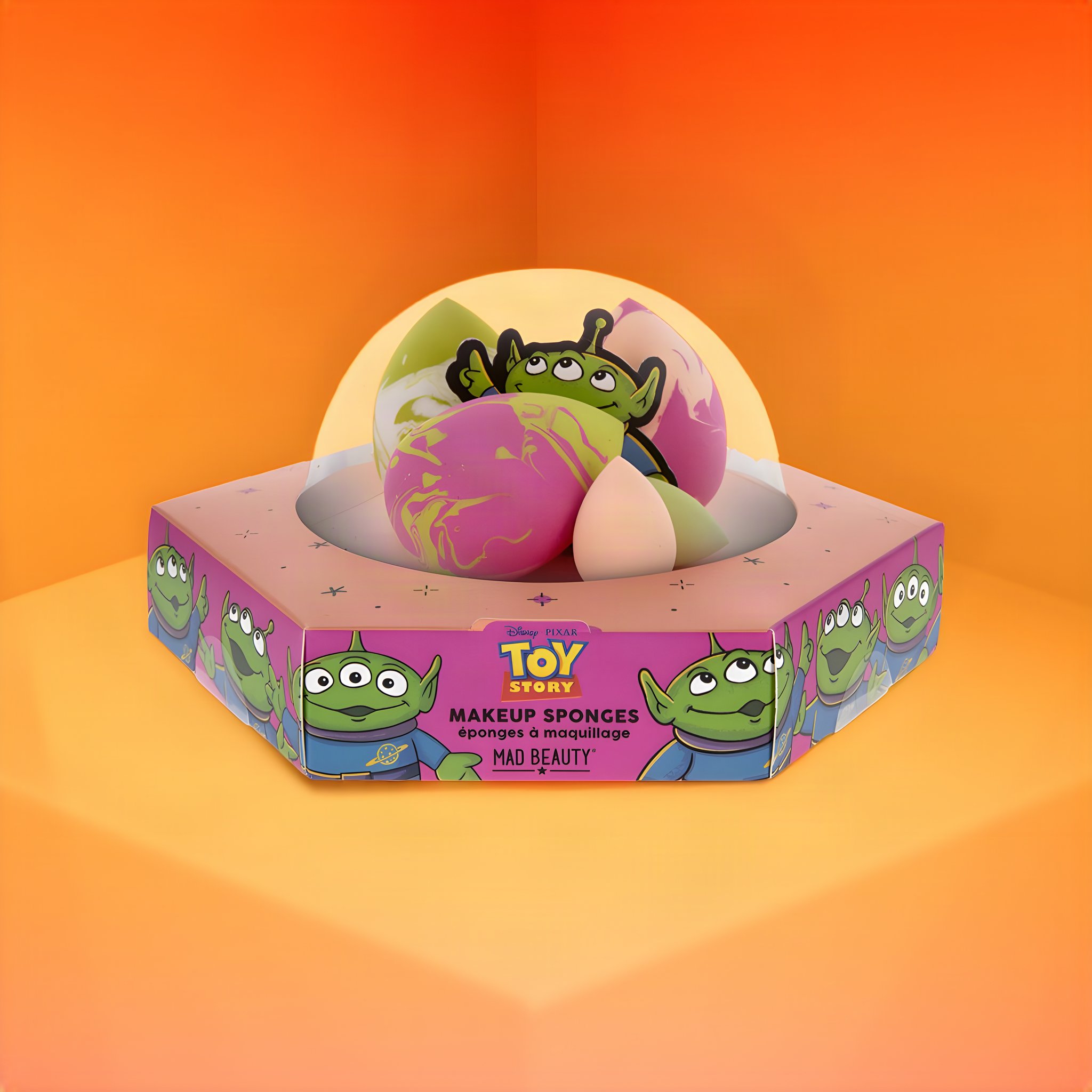 Toy Story Make-up-Schwämmchen unter der UFO-Kuppel, auf der Verpackung die grünen Aliens, oranger Hintergrund