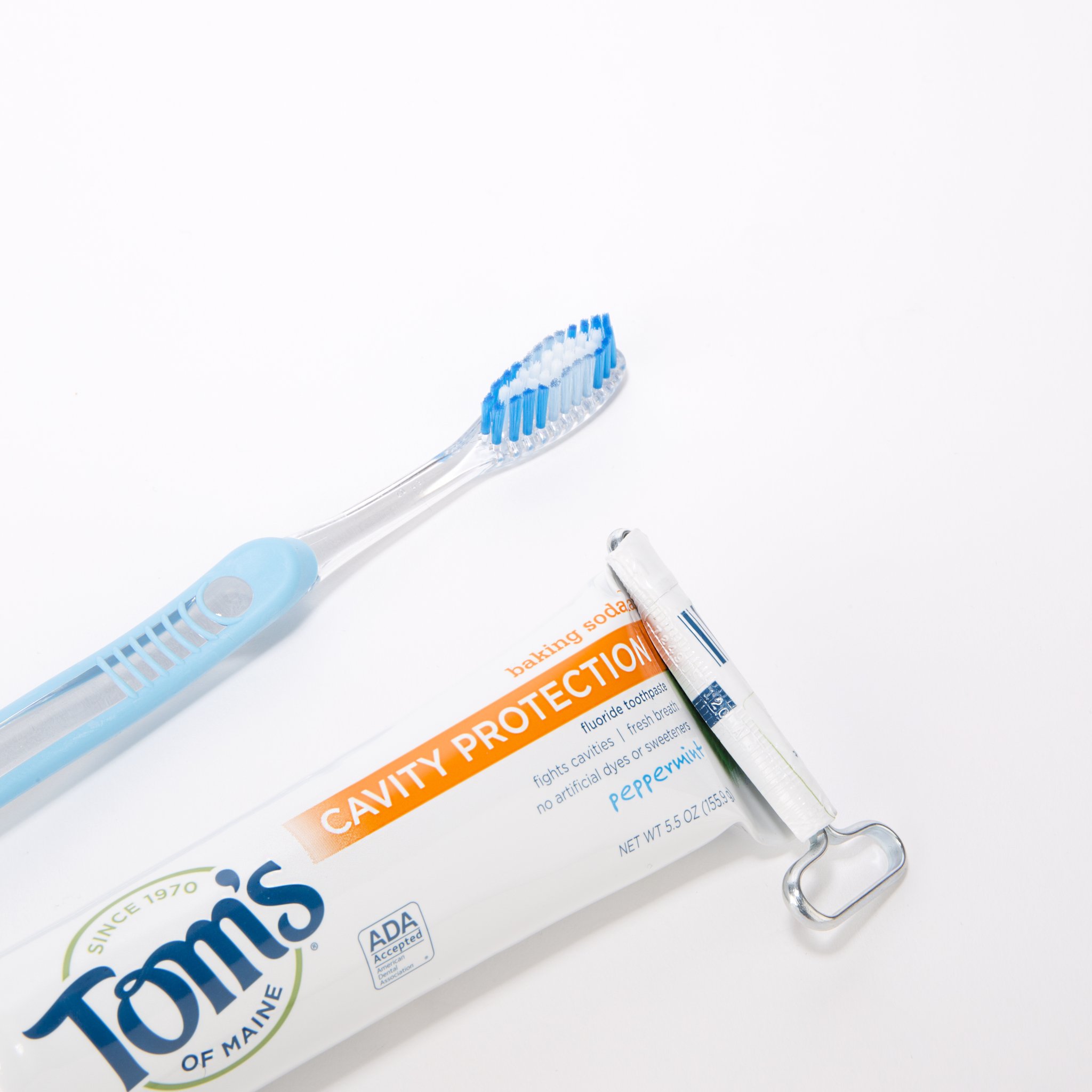 Spremitubetto all'estremità di un tubetto di dentifricio accanto a uno spazzolino