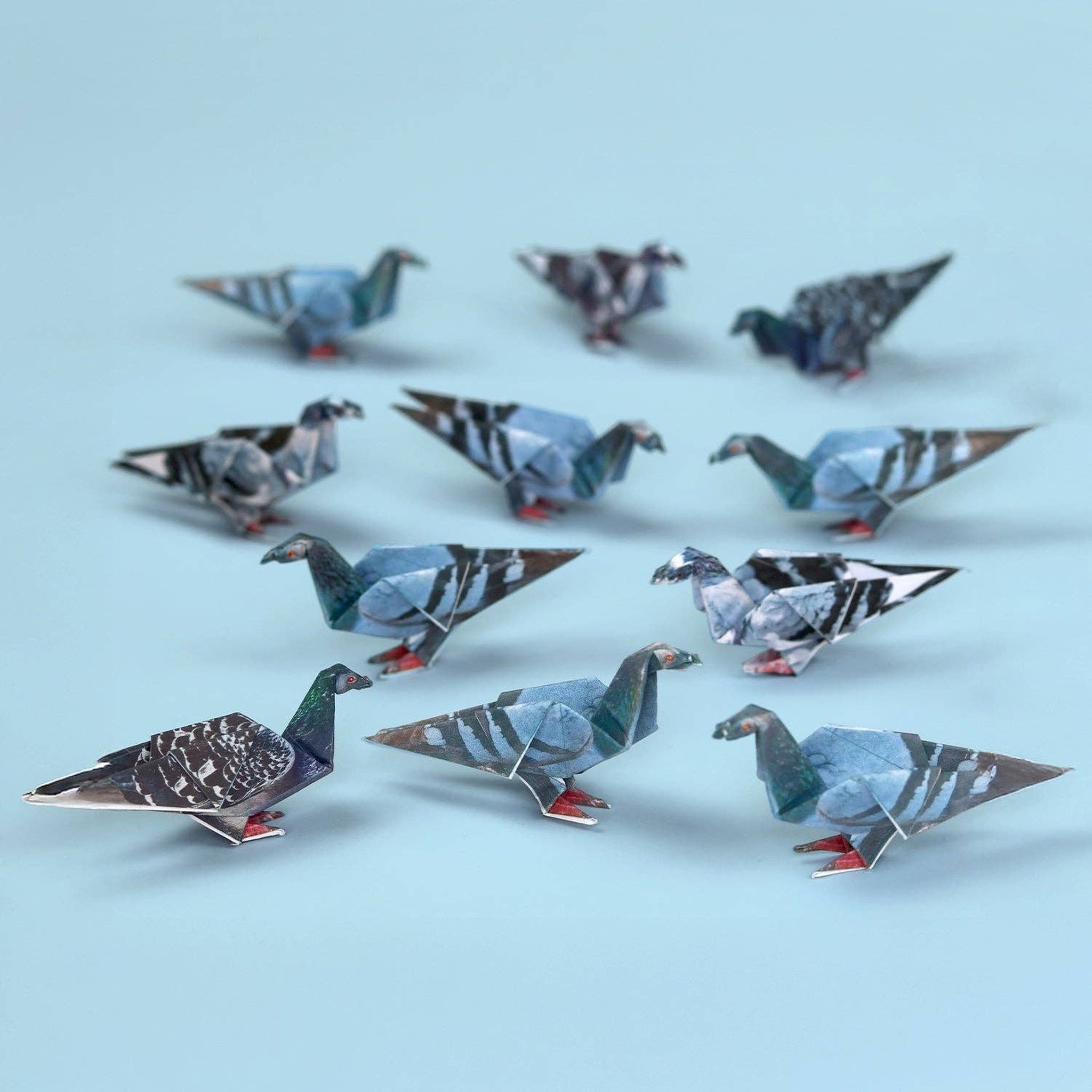 Flock of folded origami pigeons in three patterns with red feet