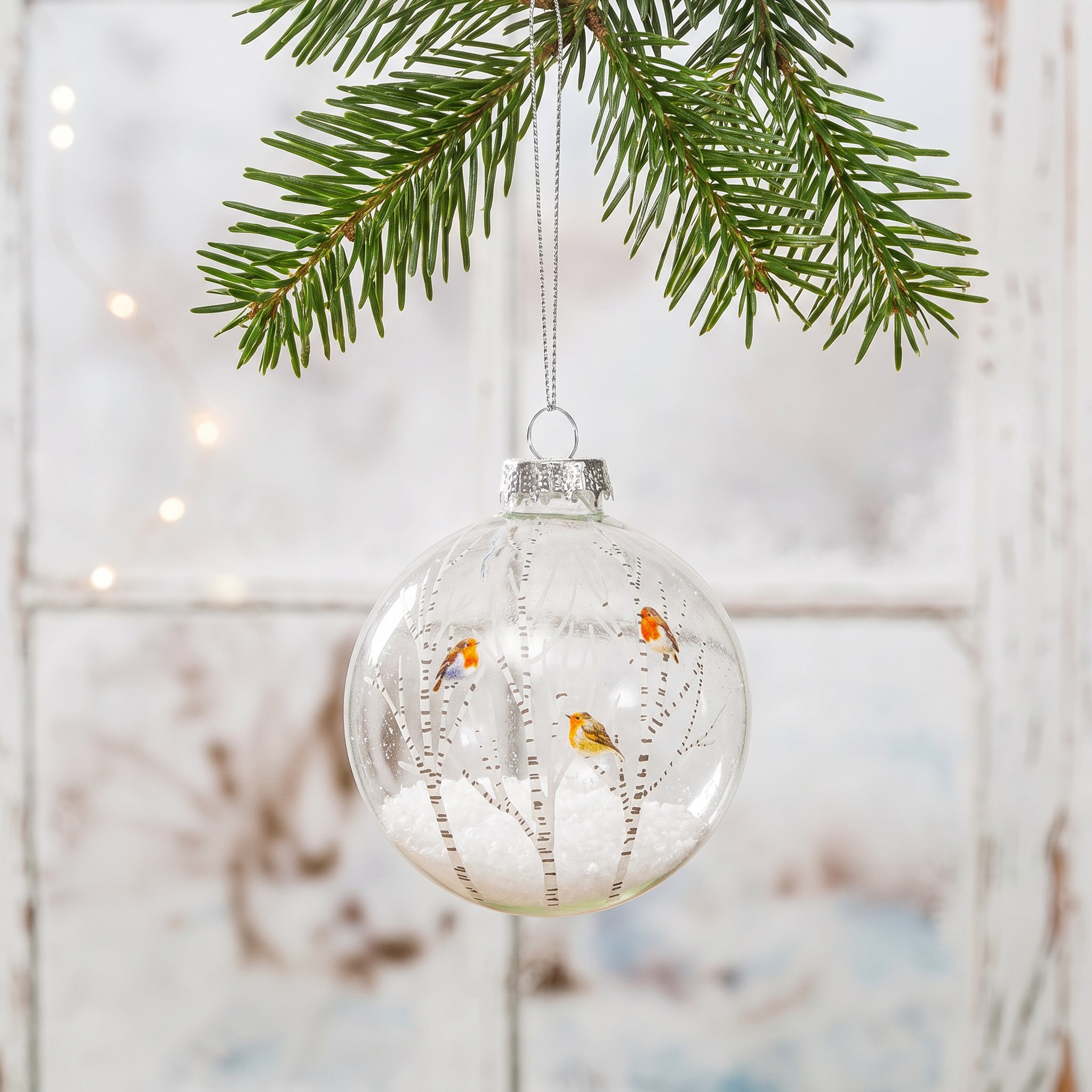 Winter Robins Christmas Bauble by Sass & Belle on a fir branch against pale wood