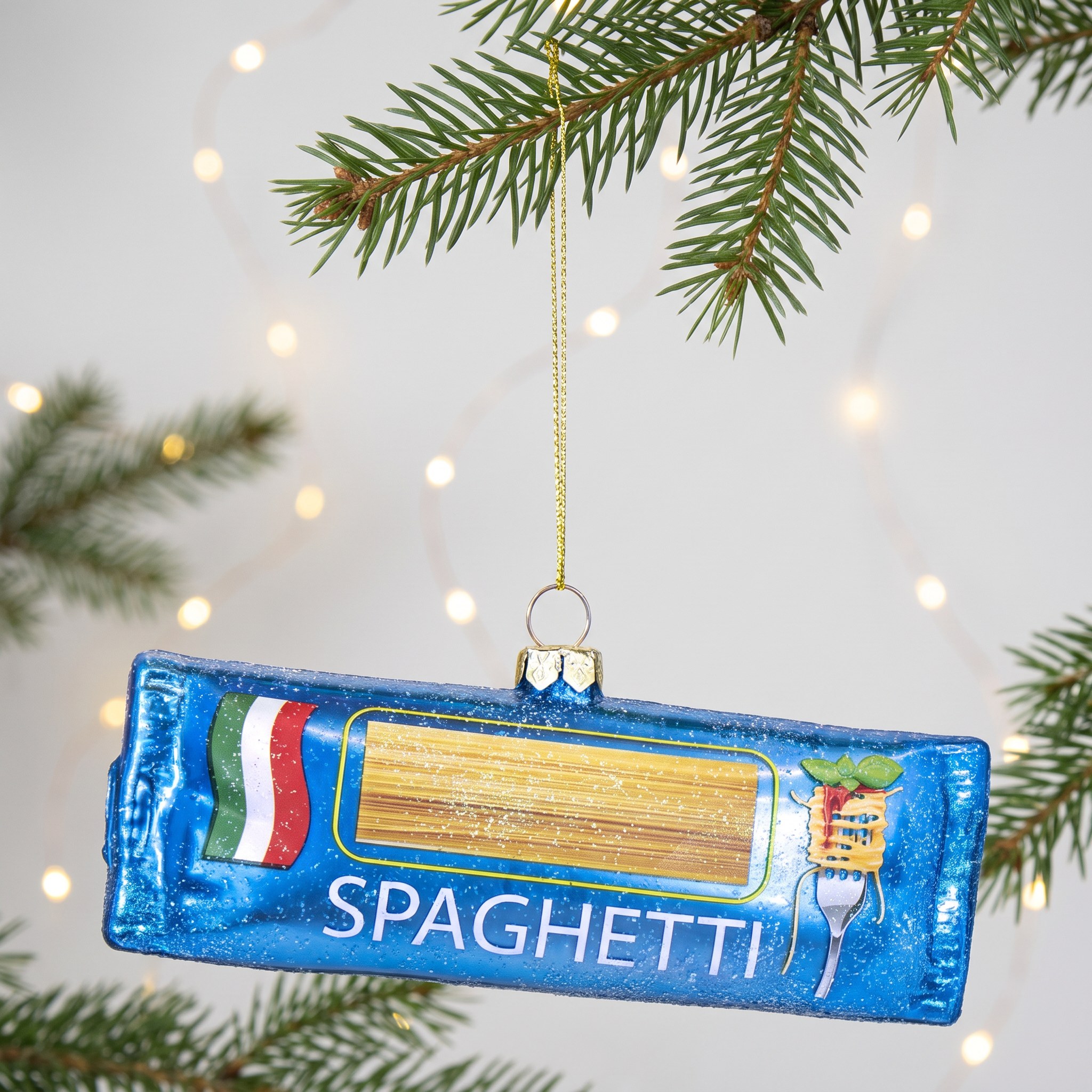 Decorazione natalizia a forma di spaghetti di Sass & Belle su un ramo di abete con luci calde