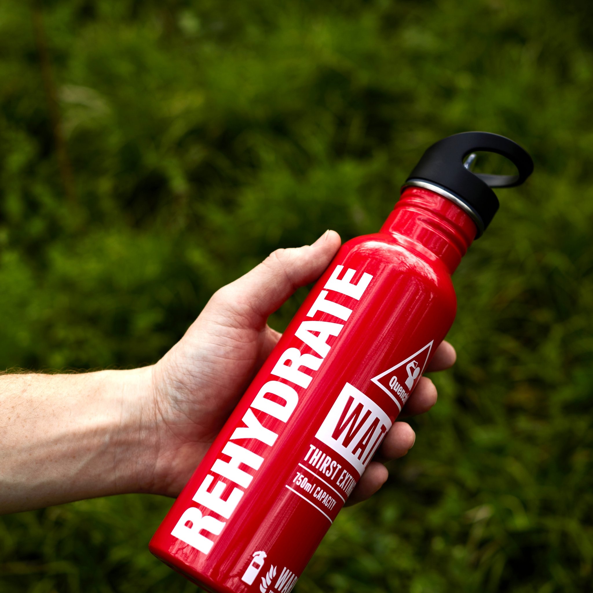Bouteille extincteur avec inscription REHYDRATE tenue en main lors d'une sortie en pleine nature