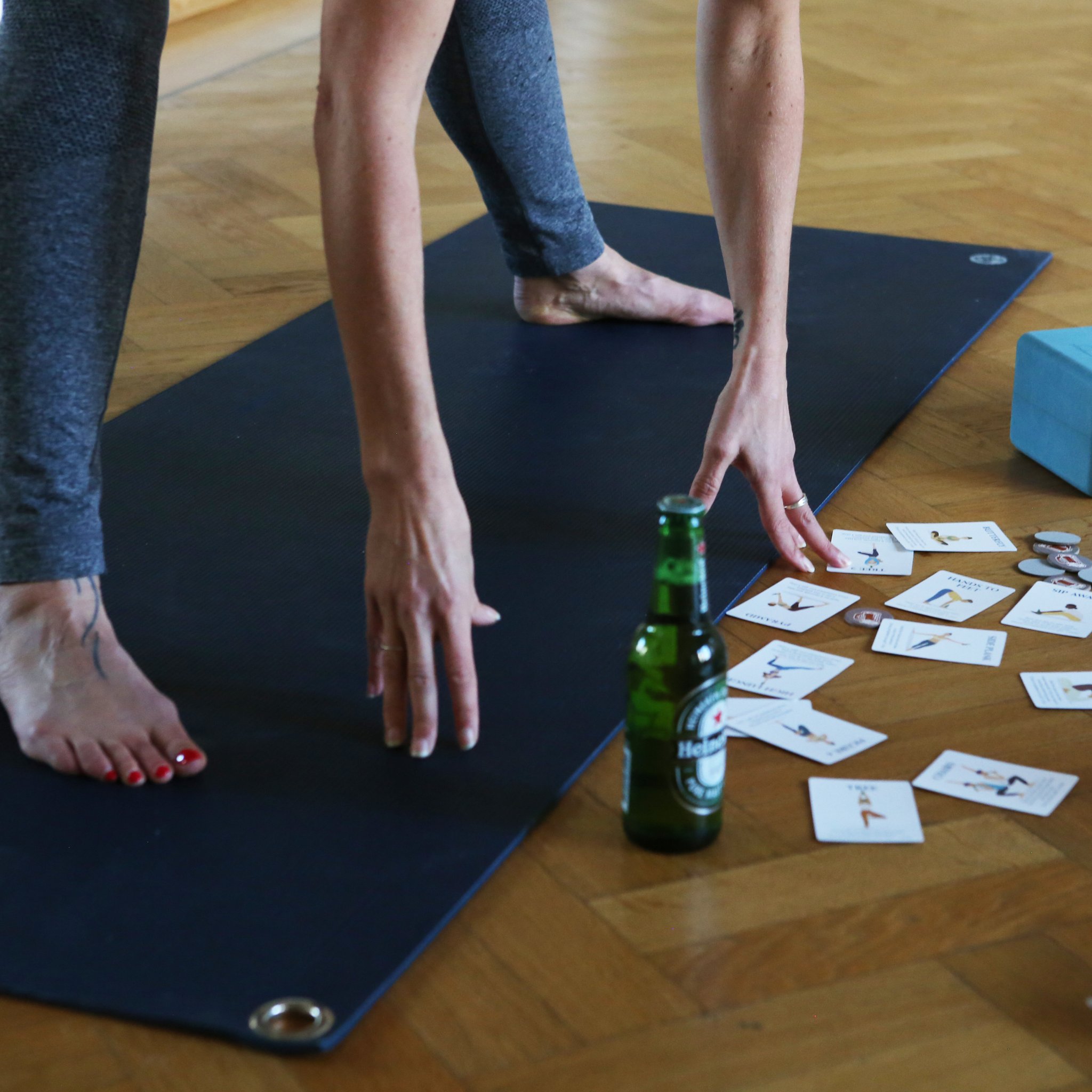 Beer yoga sur le tapis : mains, bouteille de bière et cartes