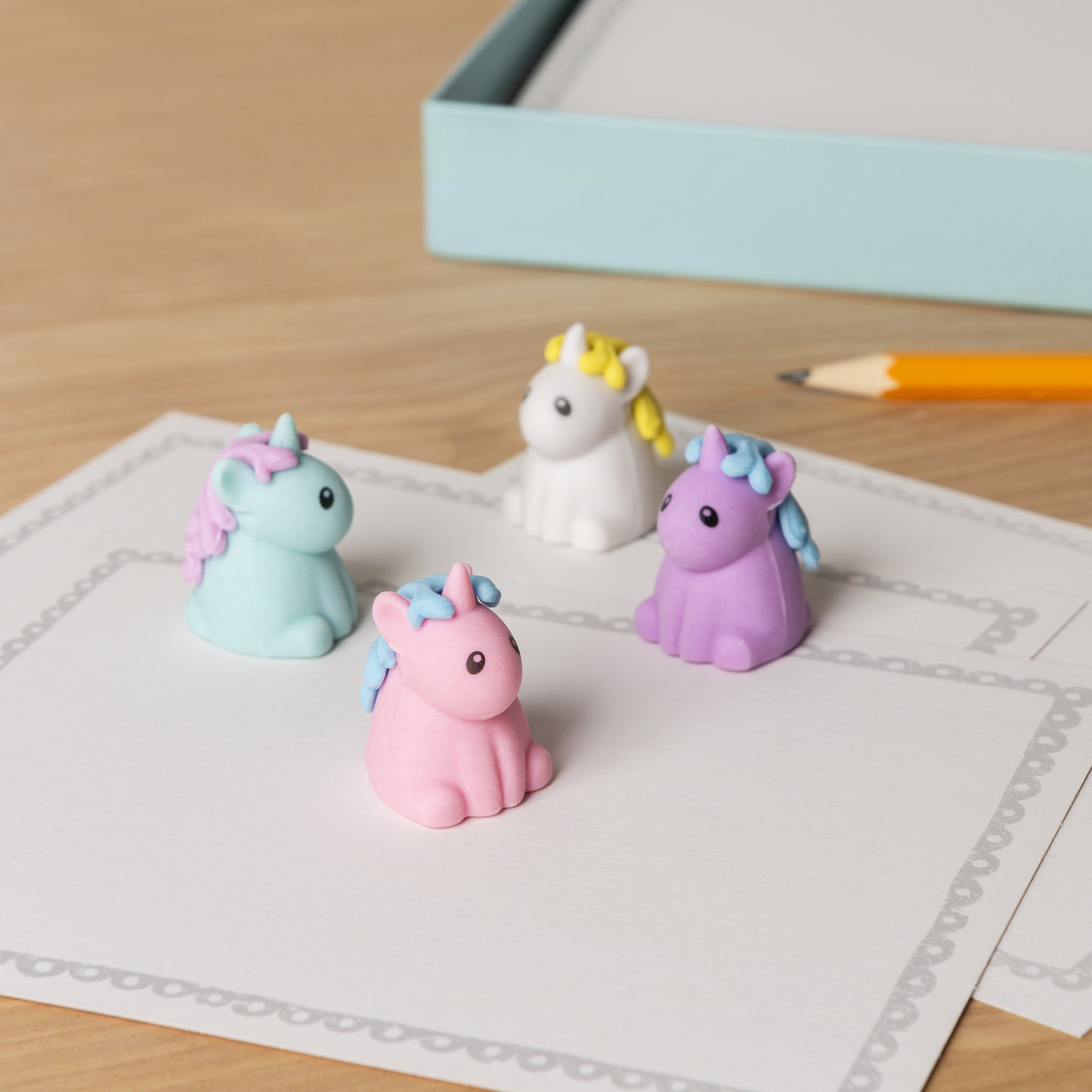 Gomme unicorno su un blocco note con matita e scatola turchese sulla scrivania