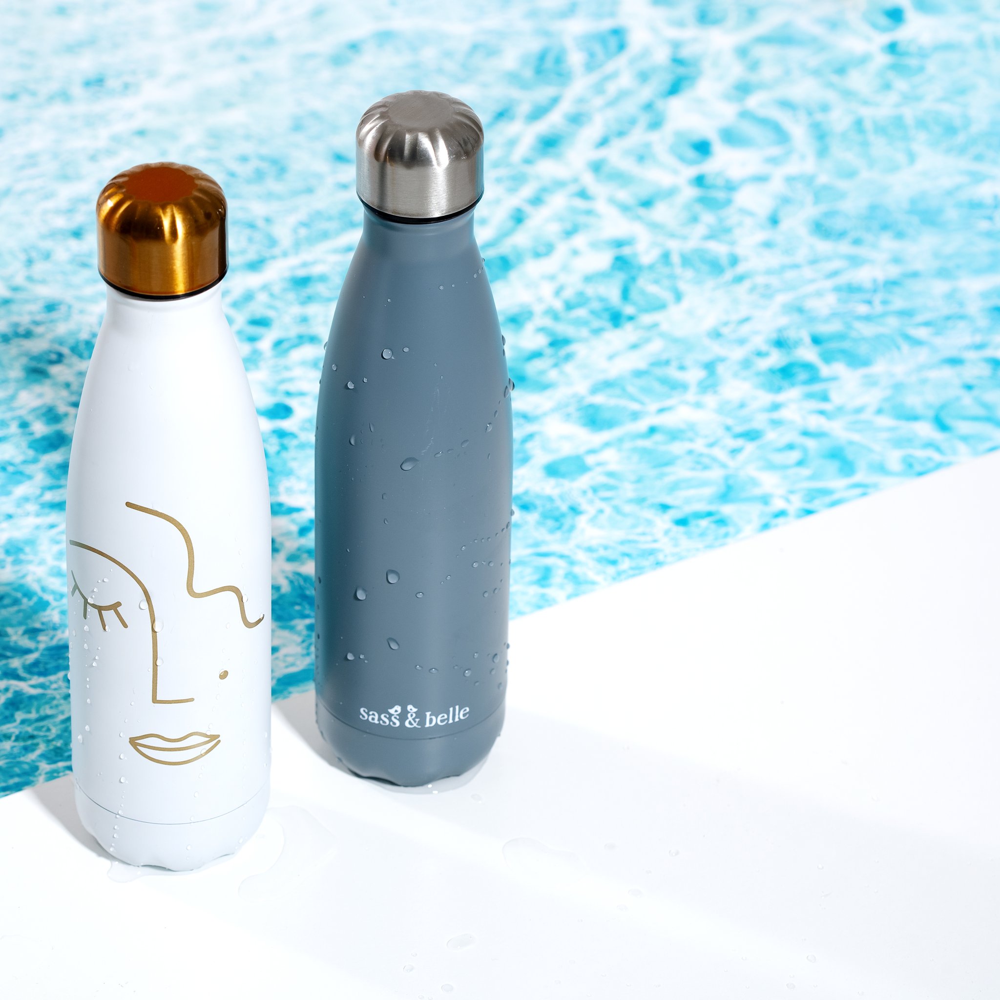 Borraccia Abstract Face accanto a una bottiglia grigia davanti all'acqua