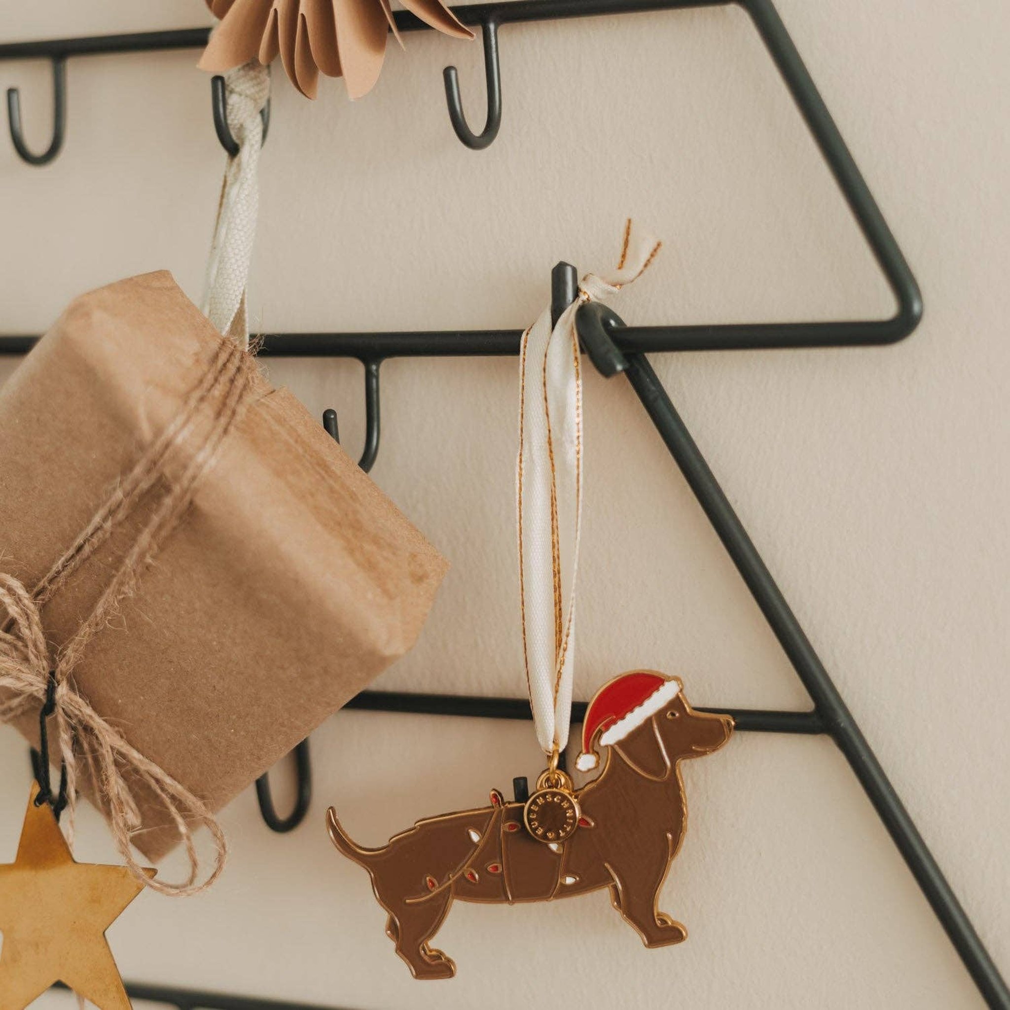 Detail mit Kraftpapier-Päckchen und Dackel-Anhänger mit Weihnachtsmütze an der Metalltanne