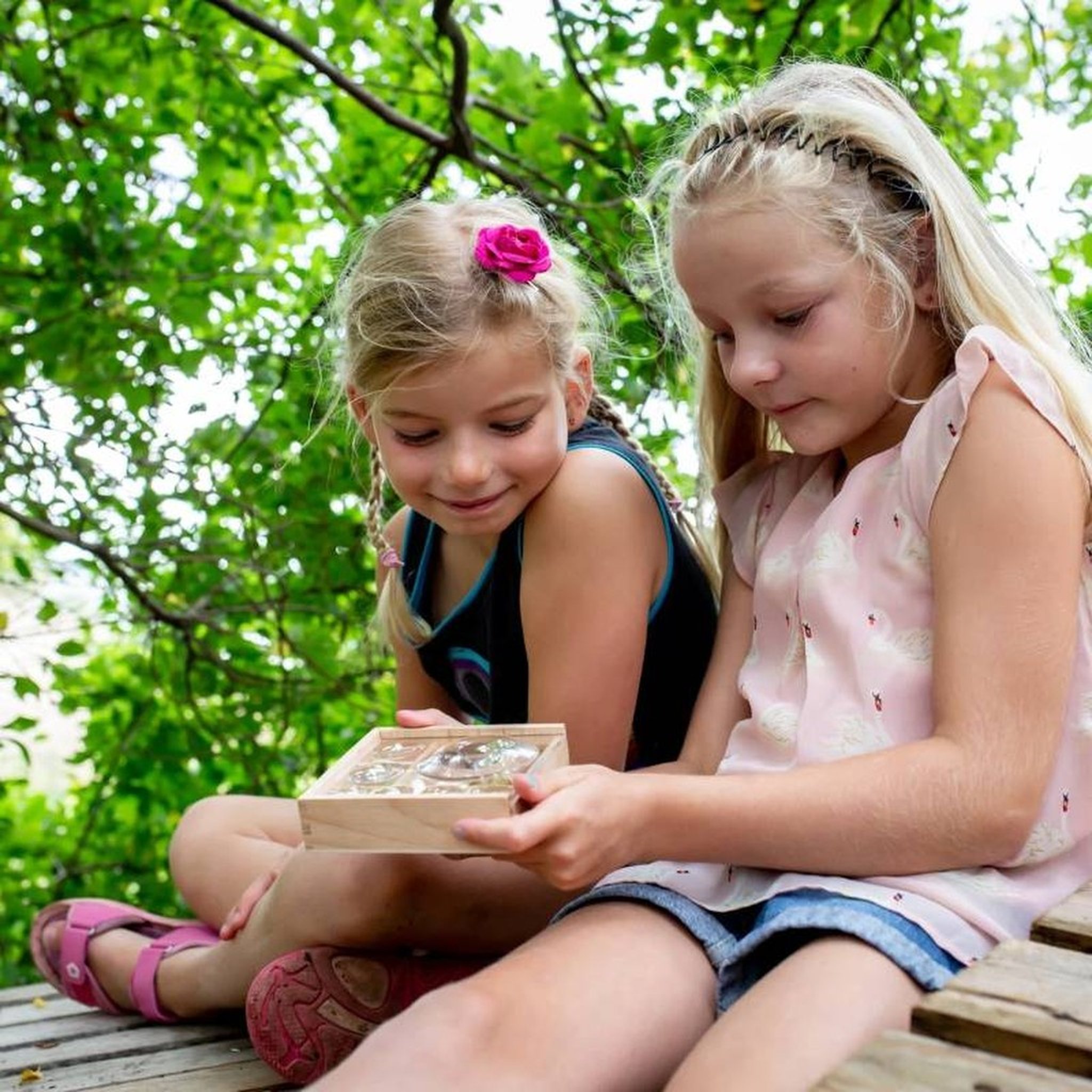 Two girls looking at the Huckleberry bug box in the garden