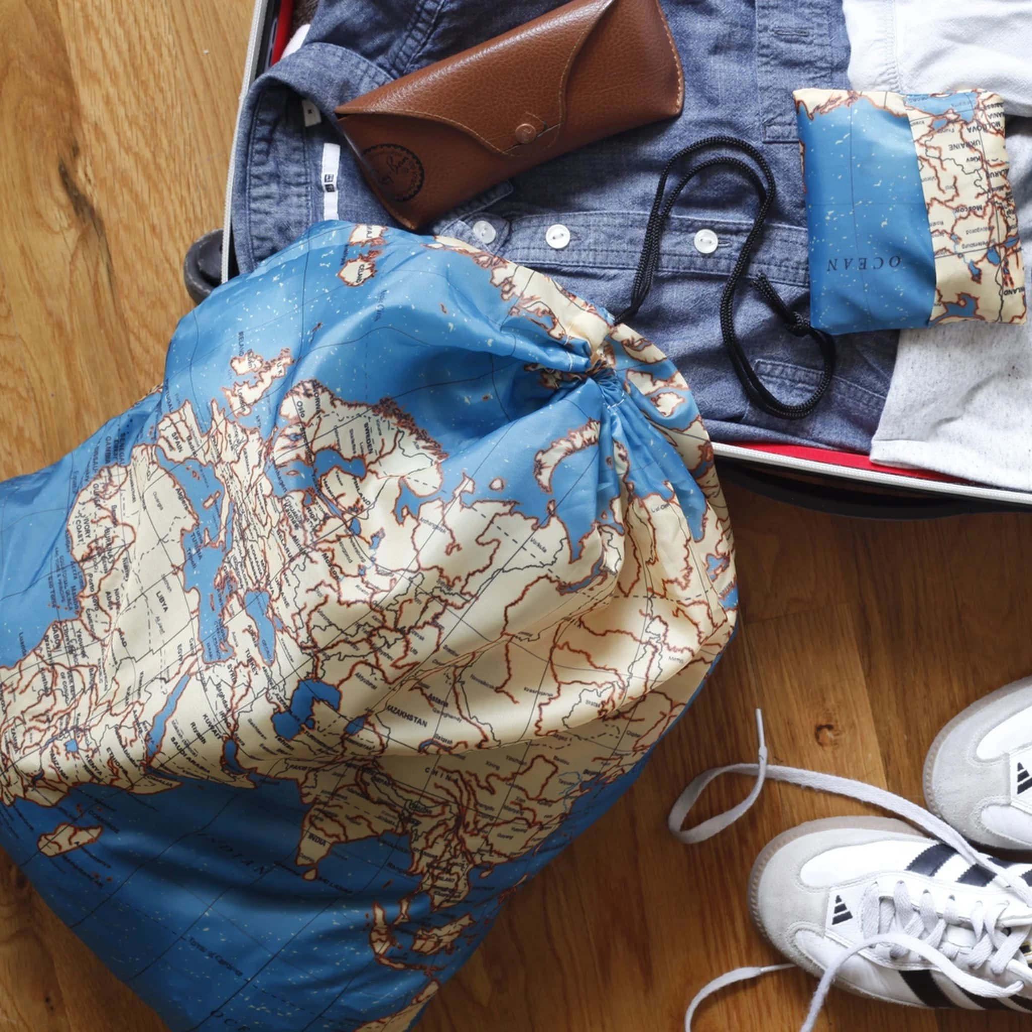 Sac à linge carte du monde dans la valise à côté de baskets