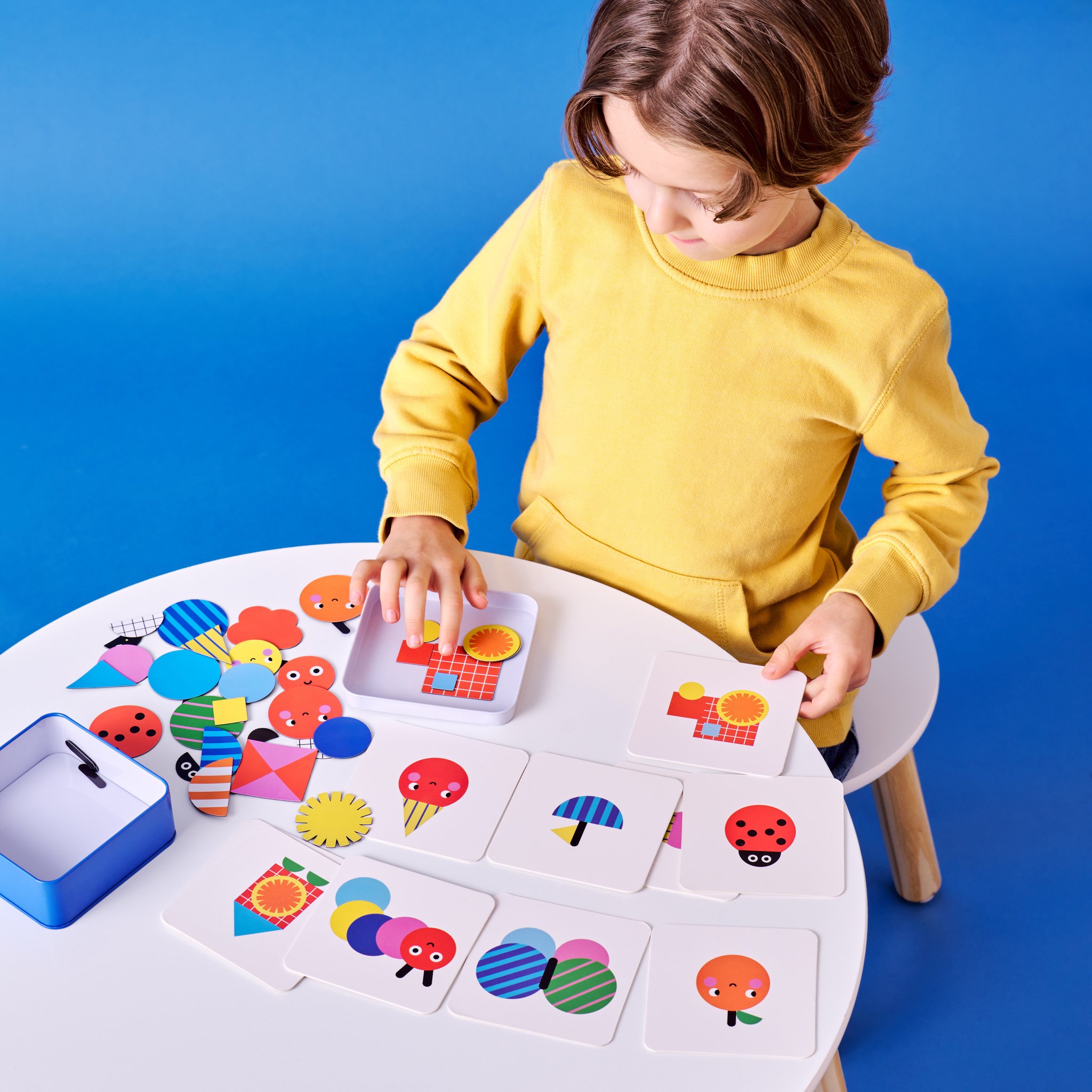 Boy at the table placing magnetic shapes on the template cards