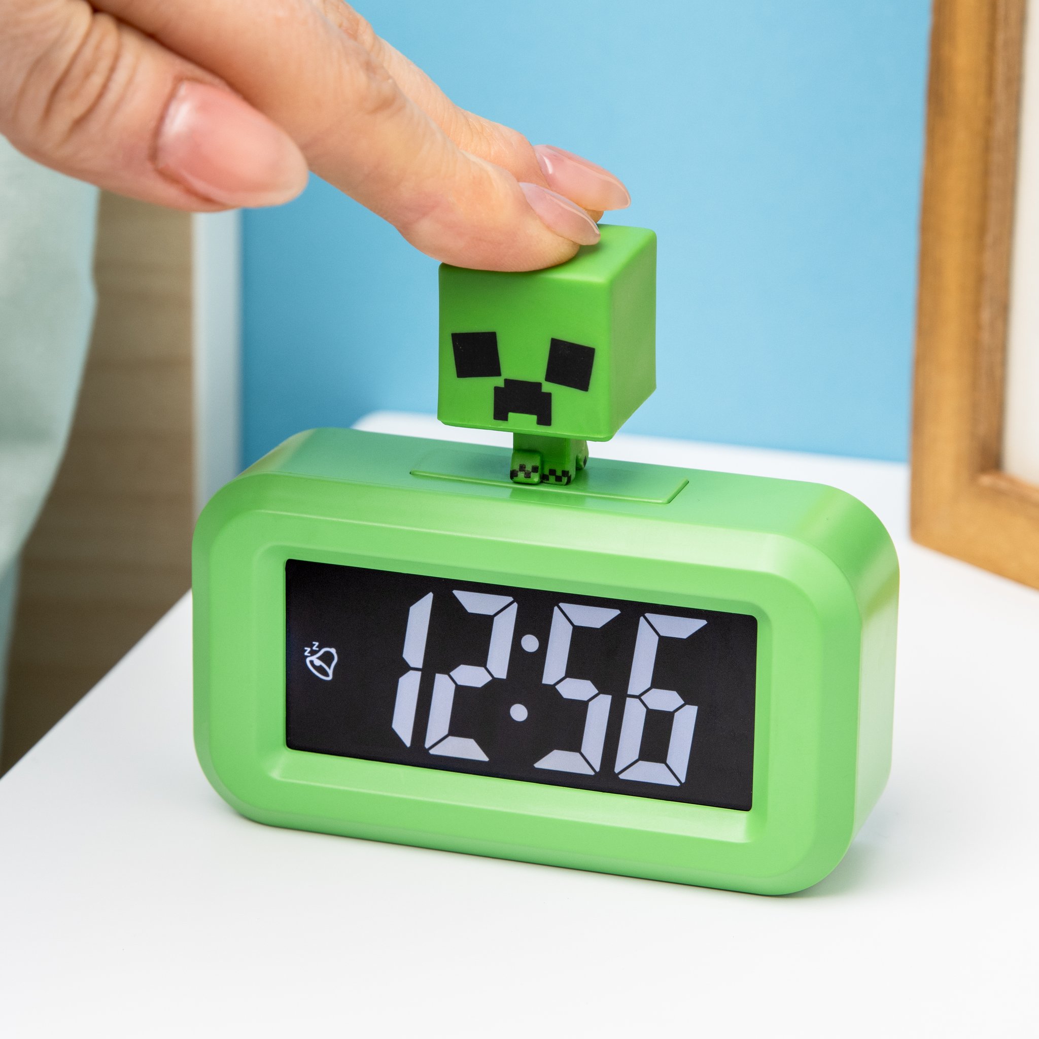 Finger tippt auf den Creeper-Kopf des Weckers